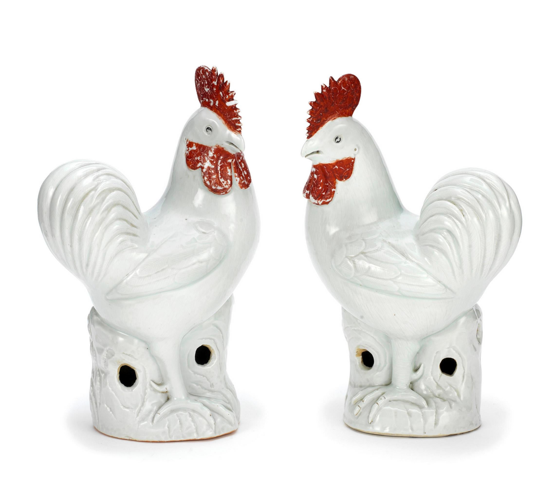 A fine pair of large 19th century Chinese Export models of cockerels, decorated in blanc de chine with red highlights. Each modelled standing on pierced rockwork with head turned to left or right, the comb and wattled cold painted in red.