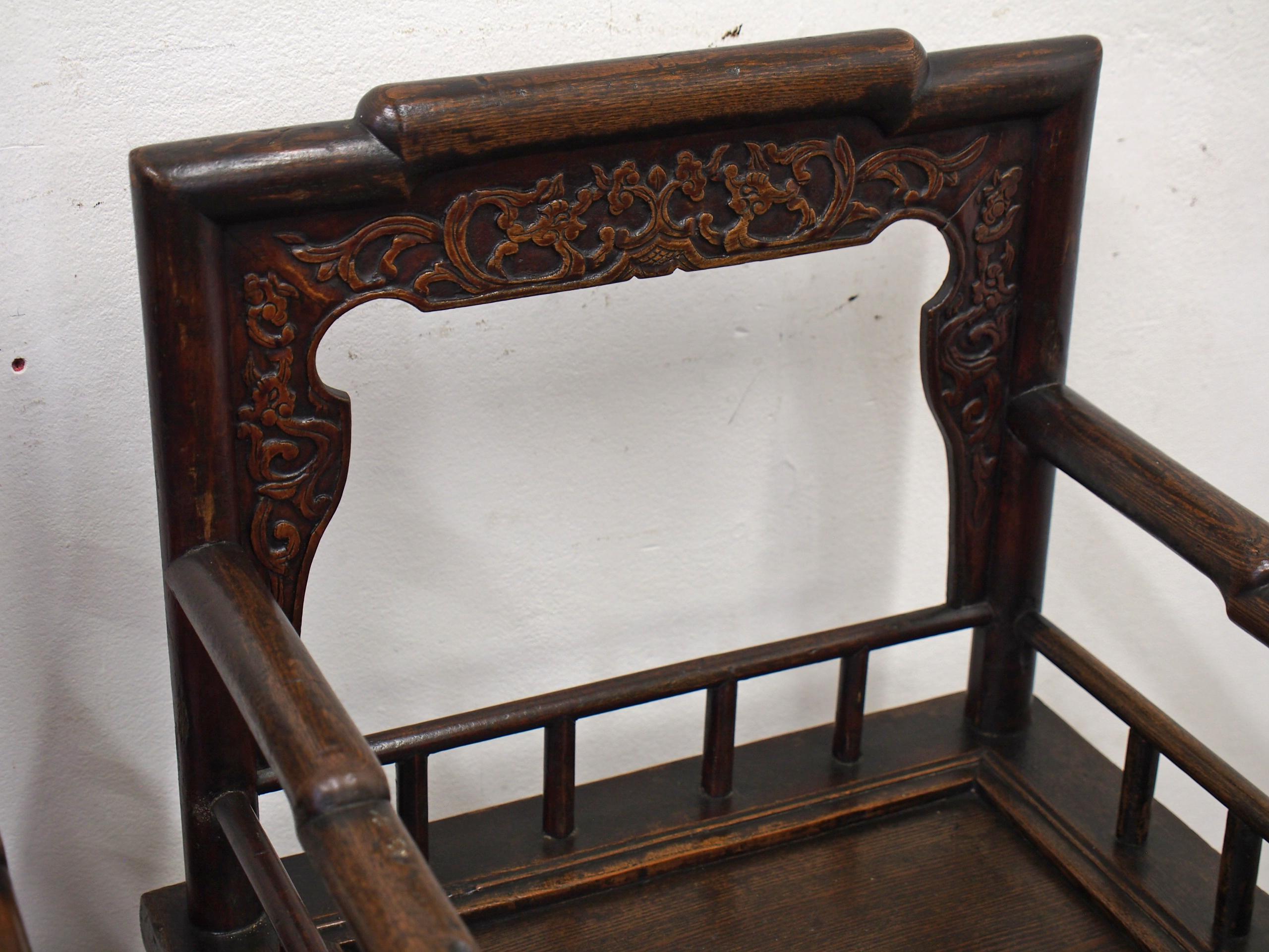 Pair of antique Chinese armchairs, circa 1850. The stepped rounded top rail leads on to rounded supports and they have an open back with floral carved moulding. The stepped rounded arms are over a lower, spindle-supported rail. With an inset panel