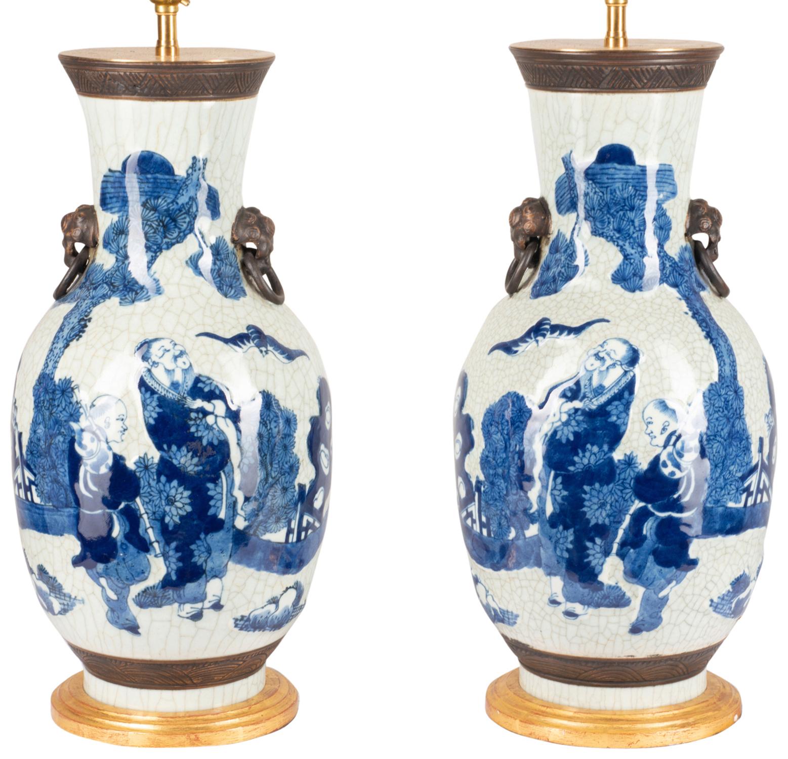 Paire de vases/lampe de bonne qualité en porcelaine bleue et blanche, chacun avec des figures orientales regardant des chauves-souris volant dans le ciel.
Montés sur des bases sculptées et dorées.