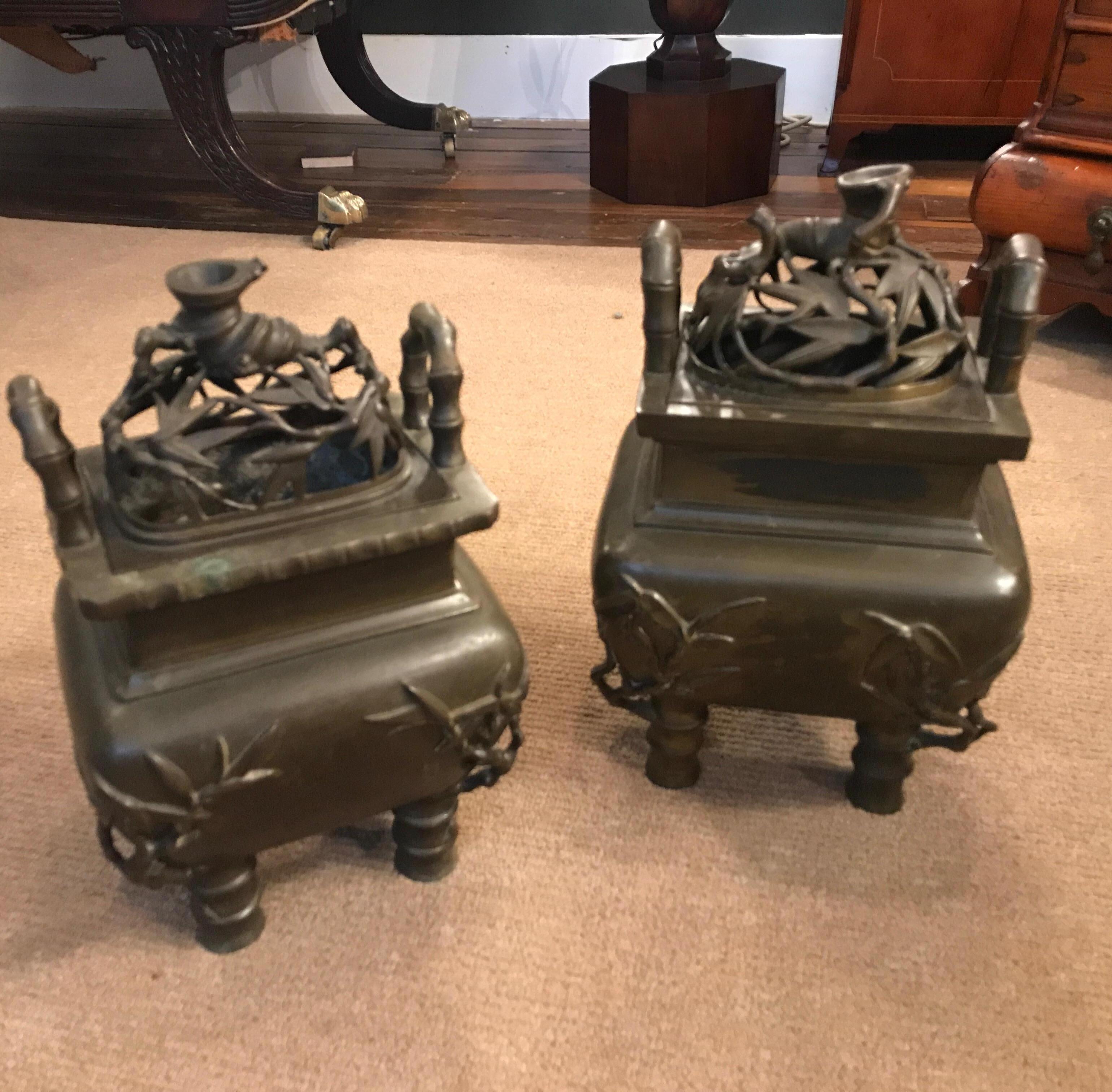 This pair is a near pair with slight differences along the upper edge the pierced tops with bamboo leaf pattern with handles on each side with a square bulbous body resting on four feet. Mid-19th century with original slightly worn patination.