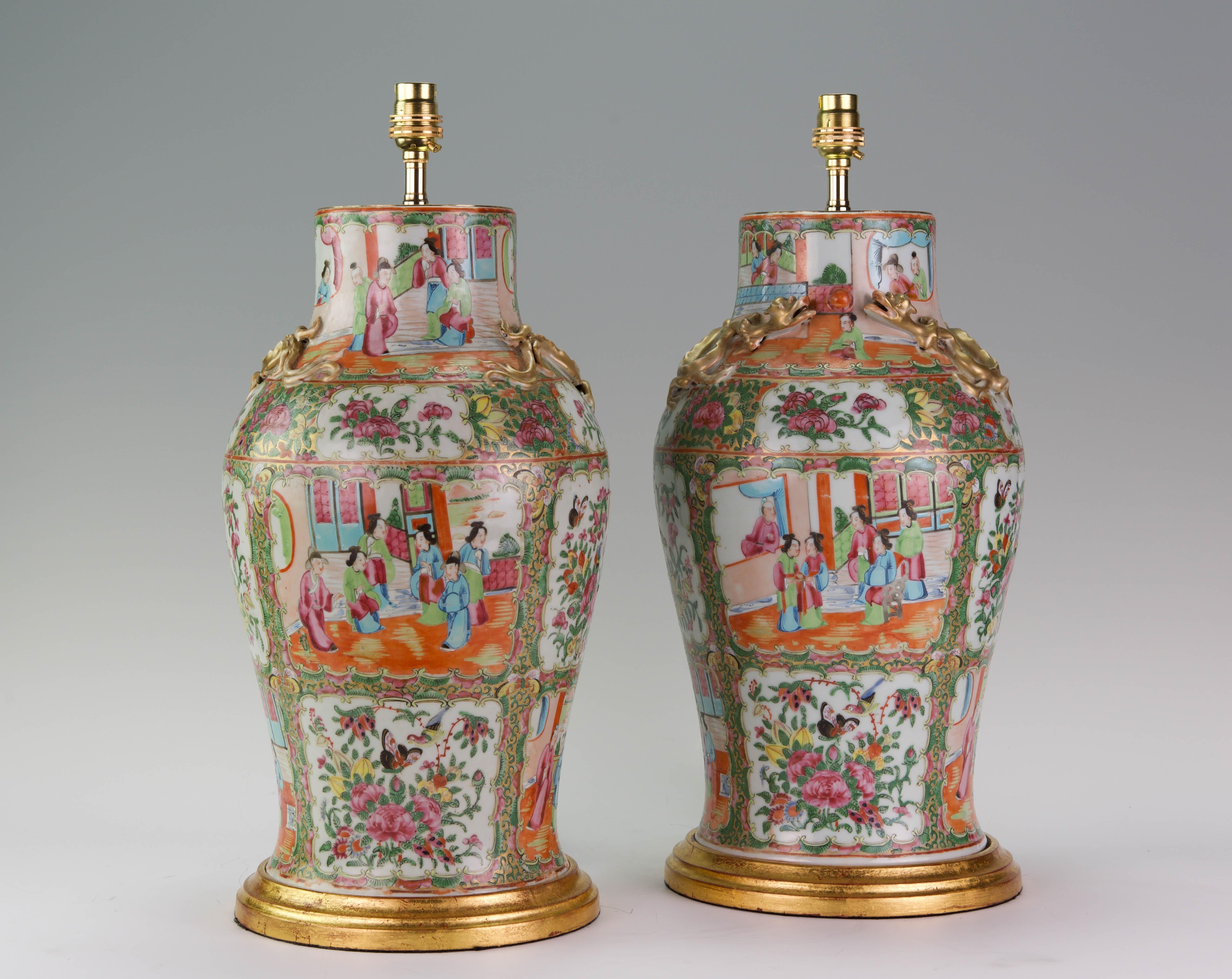 A fine pair of late 19th century Chinese Canton enamel porcelain baluster vases, decorated through in the typical rose medallion palette, with panels showing scenes of courtly life with figures in pavilions and garden landscapes, and with exotic