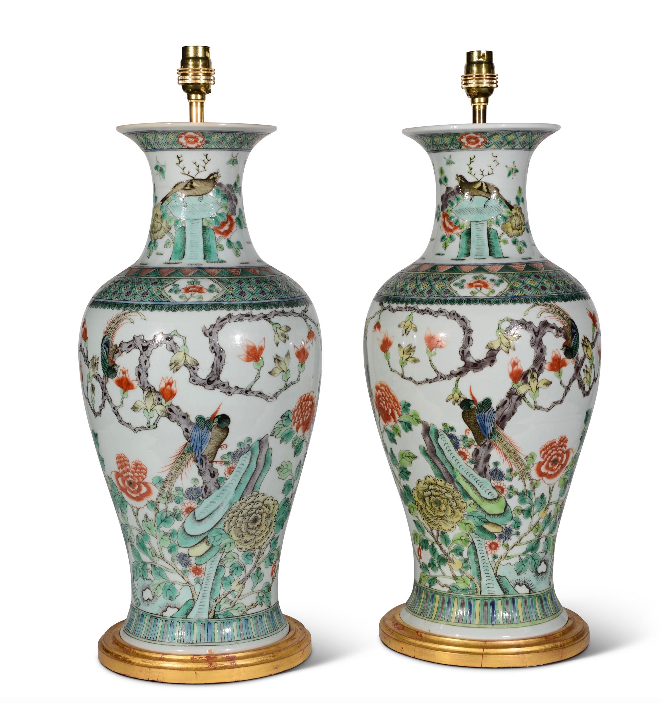 A fine pair of late 19th century Chinese famille verte baluster vases, decorated with exotic birds amongst trees and foliage and rocky outcrops with furthers stylised foliate detailing, predominantly in tones of green on a white background, now