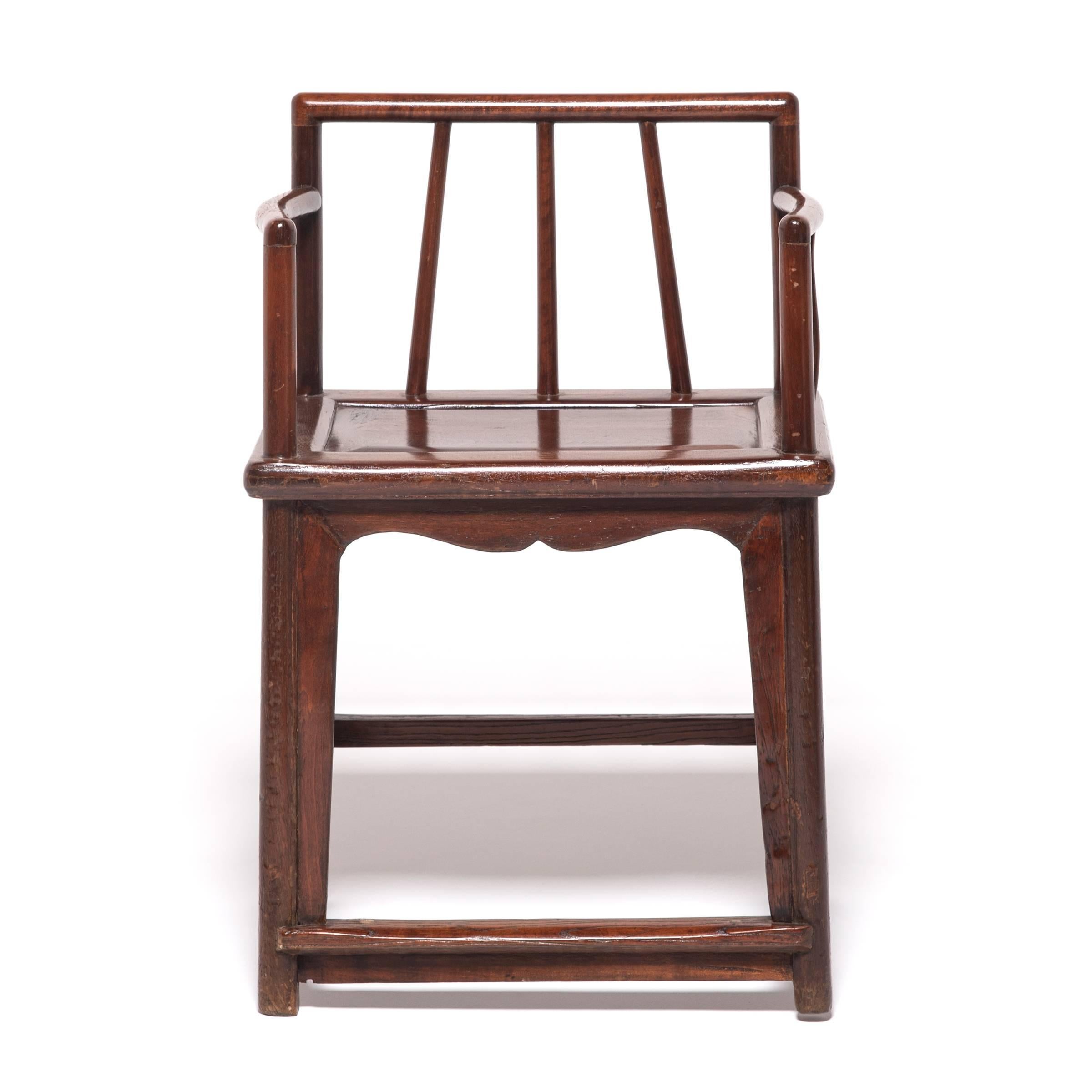 These 19th century spindleback armchairs owe their graceful design to the styles and techniques that emerged during the Ming dynasty, the golden age of Chinese furniture design. Constructed with mortise-and-tenon joinery, these walnut chairs are an