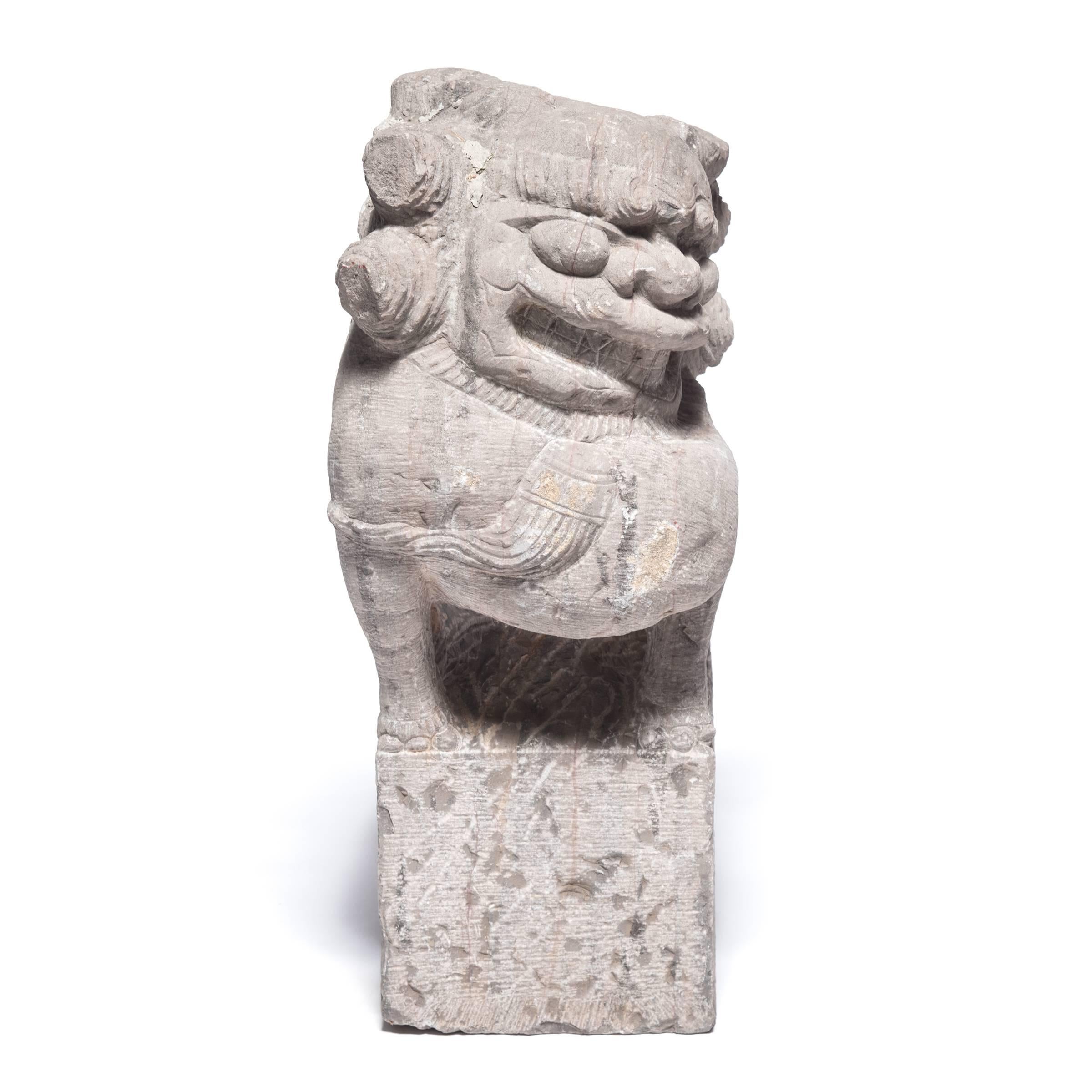 This pair of 19th century carved limestone Fu dogs with sinister smiles and furled brows once guarded the entrance to one of provincial China's grand homes. One peers up and the other down, both topped with carved manes that have bells and tassels.