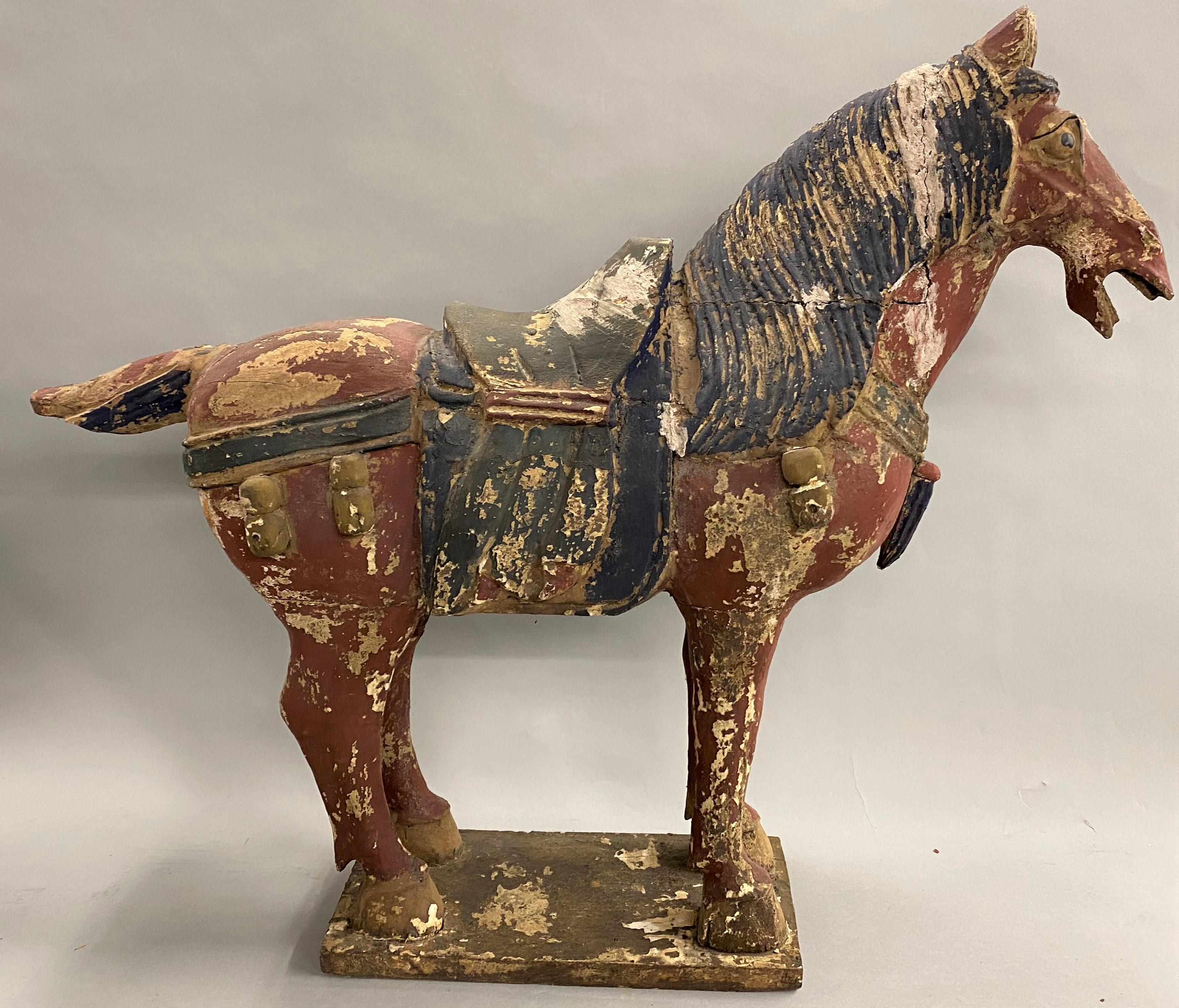 A fine pair of Chinese Tang style polychrome wooden carved horses on rectangular bases in old chippy paint, one with its head turned, probably dating to the 19th century in good overall condition, with great patina, old repairs, paint losses,