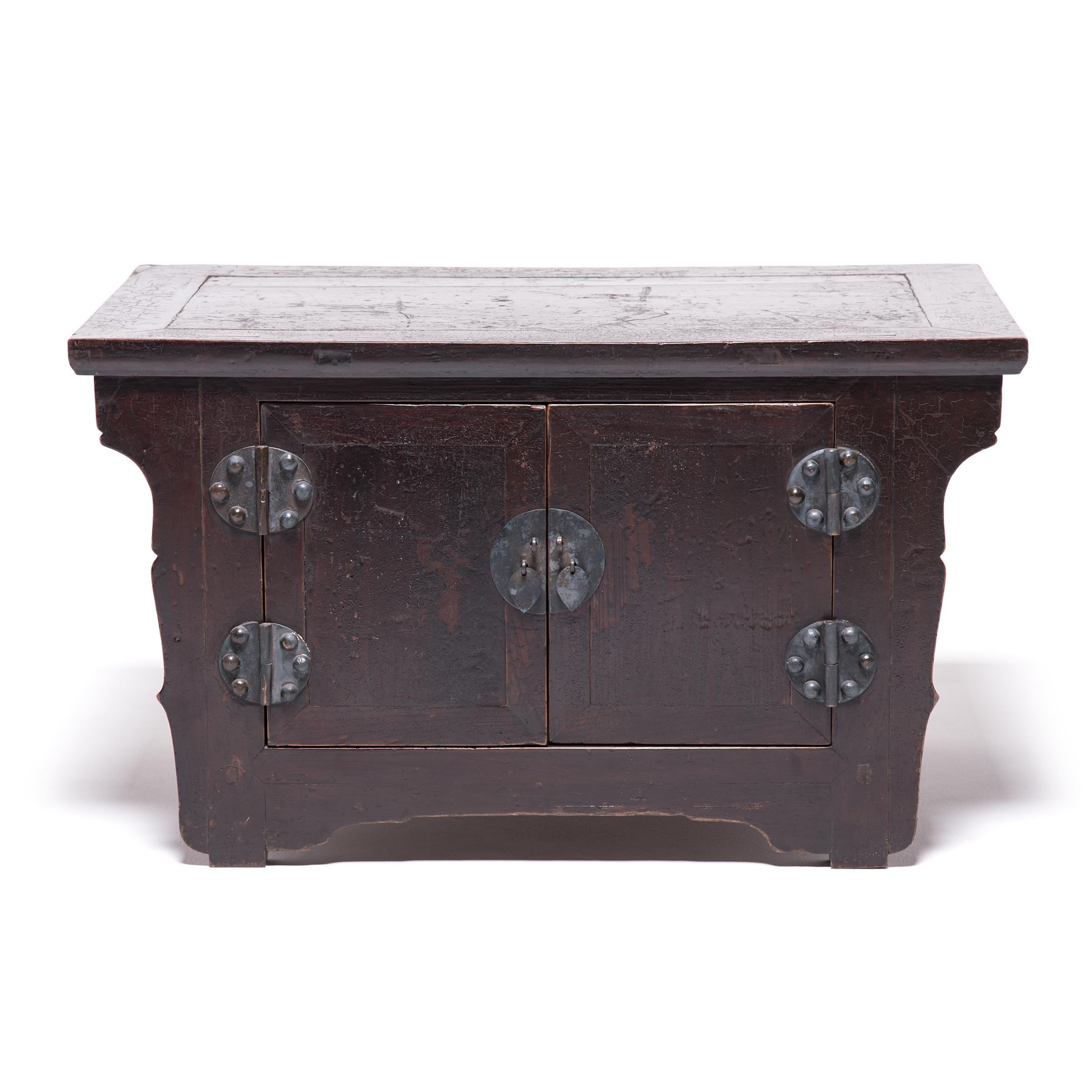 Exquisitely carved over a century ago in China’s Shanxi province, this pair of mid-19th century elmwood cabinets would have been placed upon a kang bed and used to store useful or intimate items. The beautifully scalloped edges and unusual, round