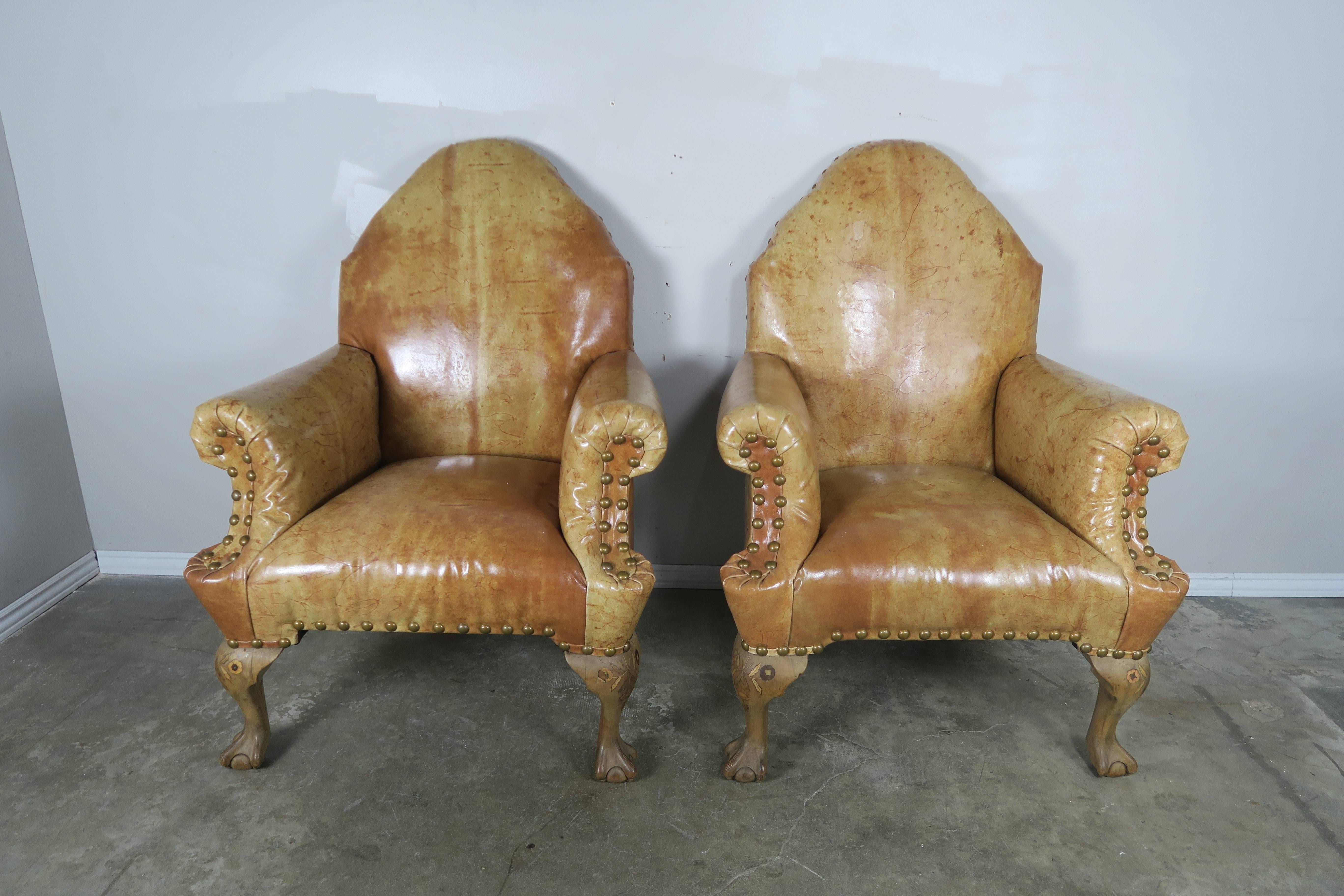 Pair of Chippendale style English leather upholstered armchairs with beautiful inlaid legs with ball and claw feet. Brass nailhead trim detail.