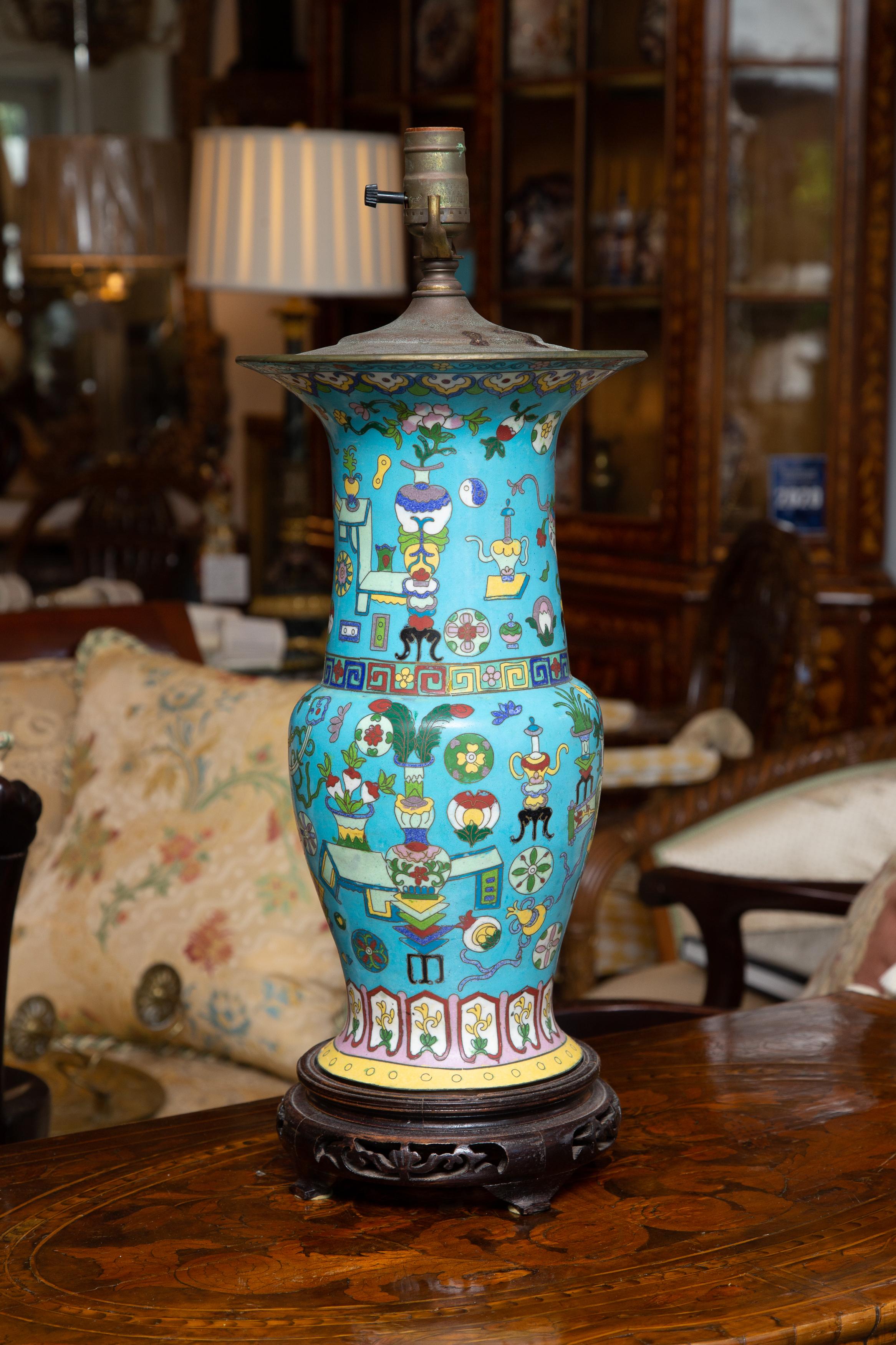 This is a lovely pair of cloisonné turquoise lamps painted overall with colorful figures and images, situated on pierced rosewood bases, 19th century.