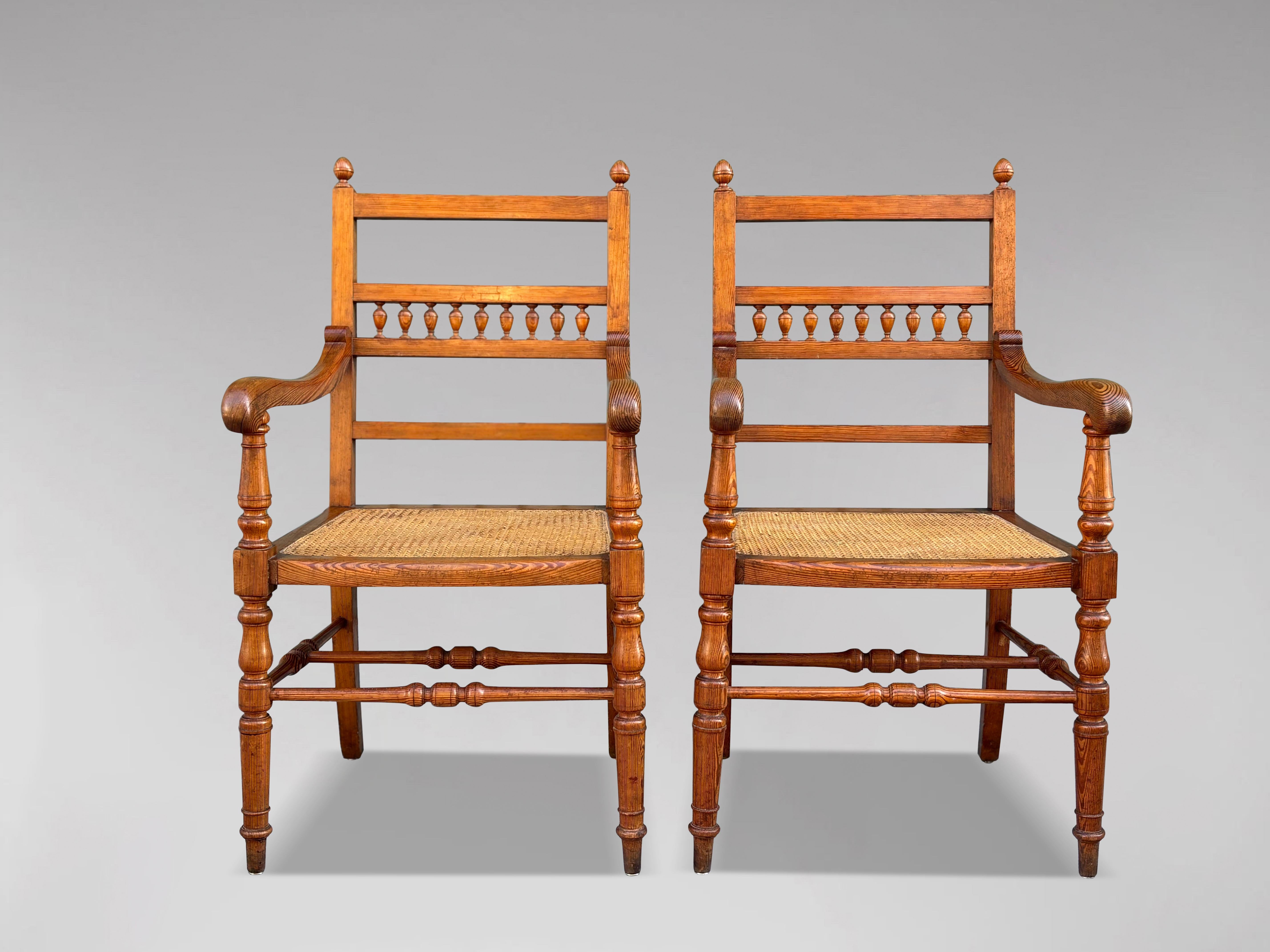 This is a superb quality pair of pitch pine country farmhouse spindle-back cane-seated kitchen armchairs, dating from circa 1880, and they are in good condition. Their exceptional quality is matched by a fantastic colour that enhances their appeal.
