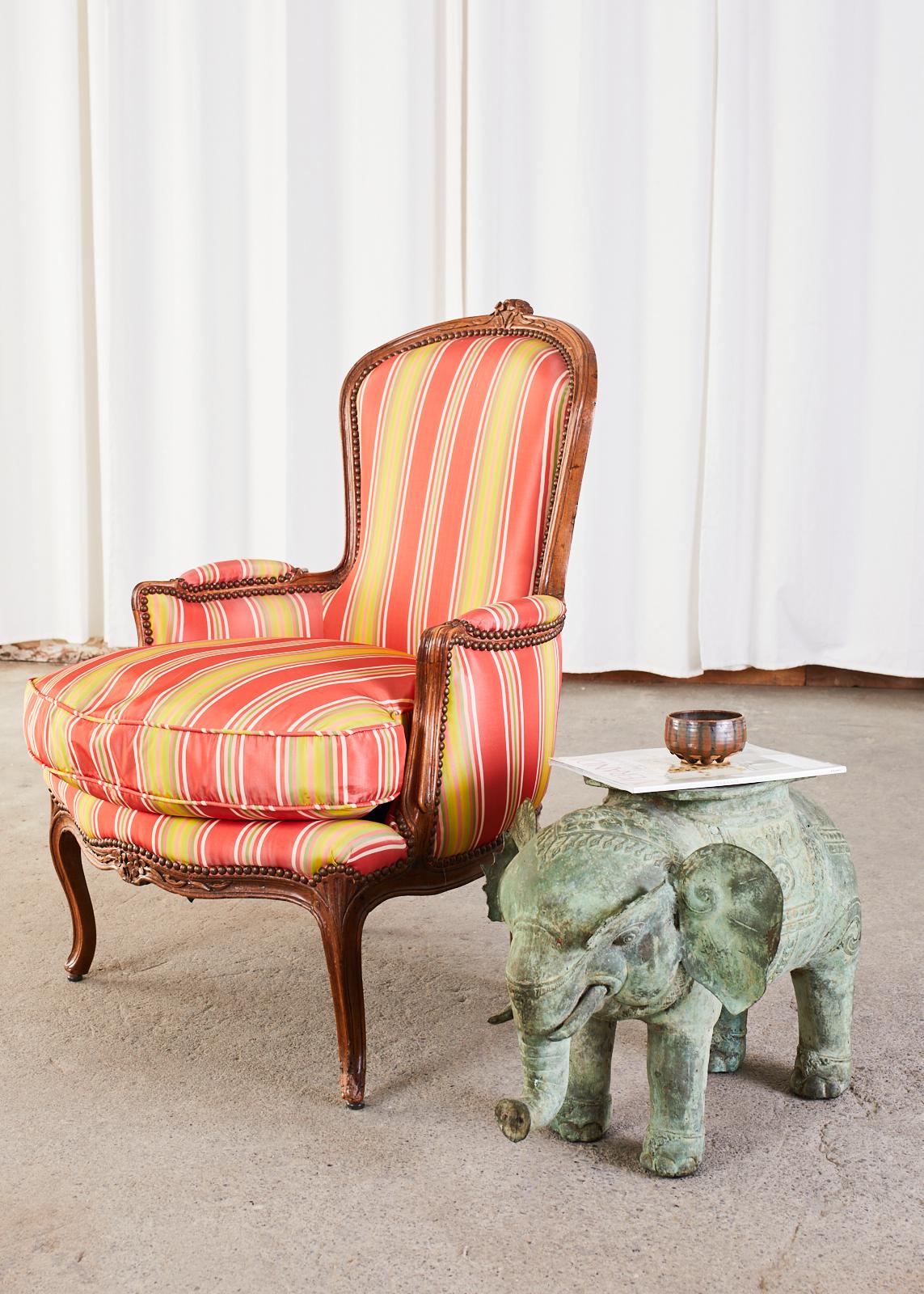 Paire de fauteuils bergère restaurés du 19ème siècle en noyer. Presque identiques, fabriquées dans un style pour elle et lui, l'une des chaises étant plus haute de 5 cm au niveau du dossier et présentant une crête florale plus grande sur le dessus.