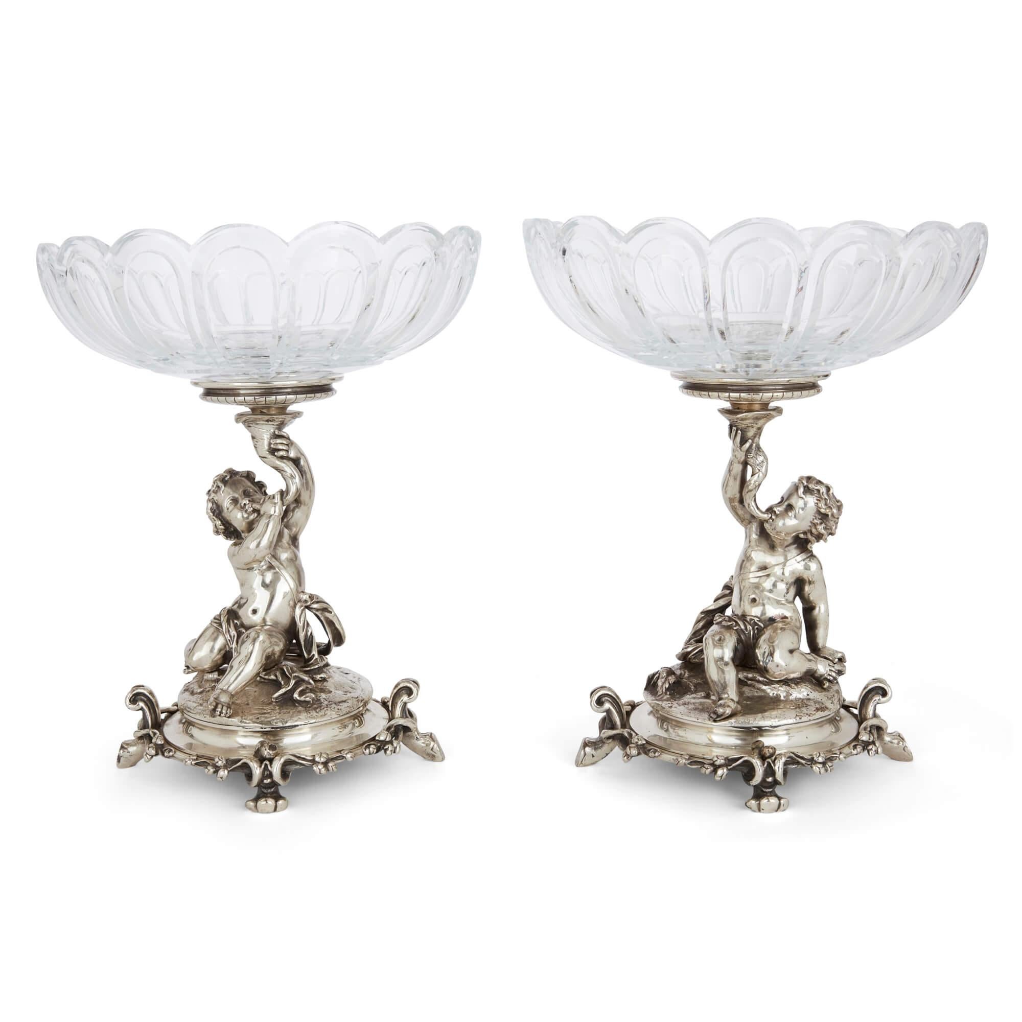 Pair of 19th century cut-glass and silvered bronze compotes by Christofle 
French, 19th Century 
Height 30cm, diameter 25cm

Crafted in the lavish Rococo Revival style, this exquisite pair of compotes pair cut-glass tazza-like bowls with sculptural