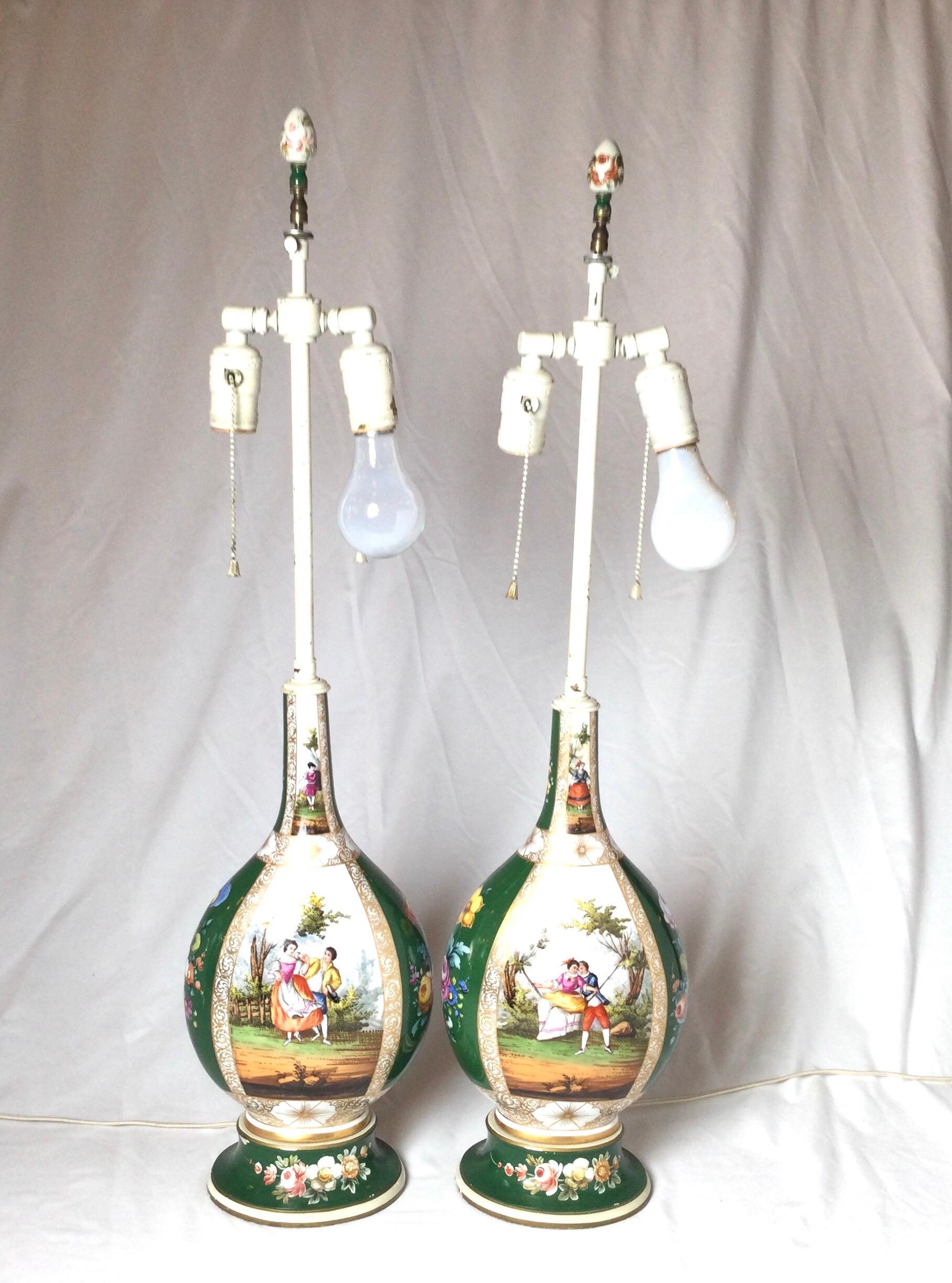 A pair of hand painted Dresden Porcelain vases now as lamps. The 19th century porcelain with hand painted courting couple scenes on the fronts and backs with dark green panels with floral decoration. These lamps were electrified in the early part of