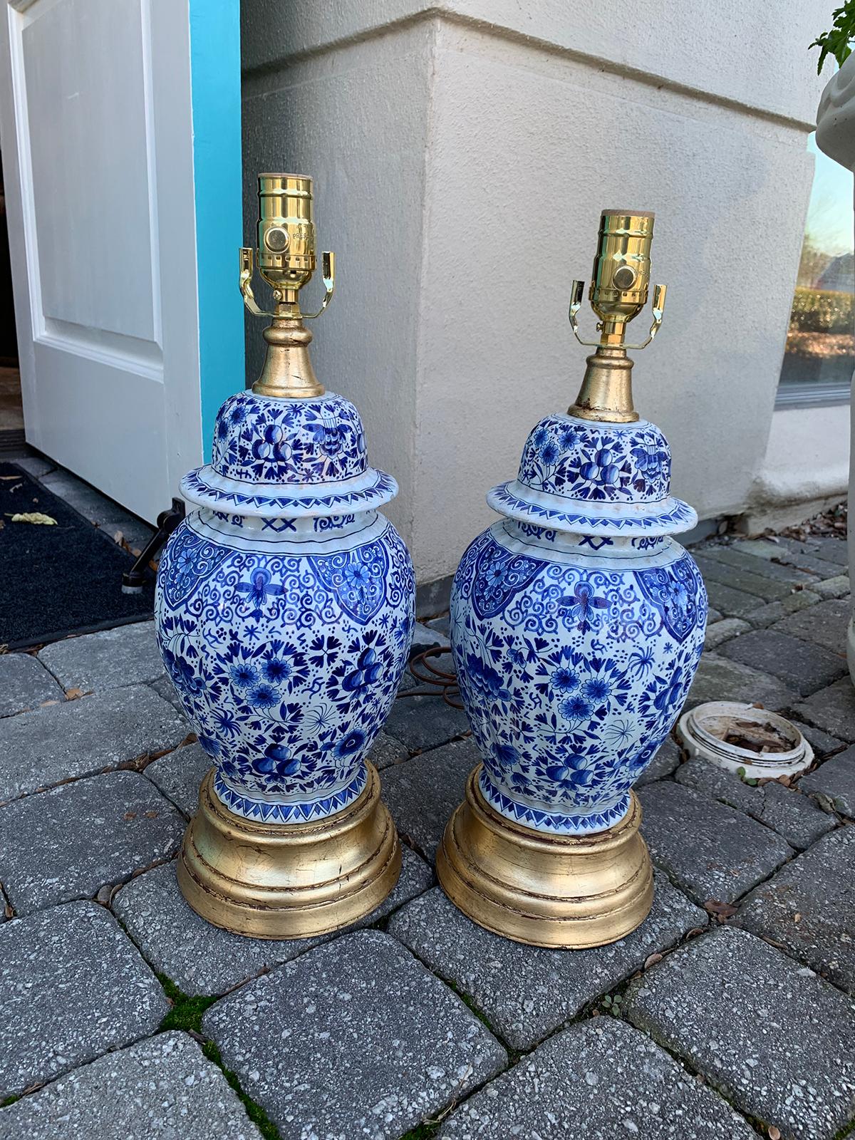 Pair of 19th century Dutch delft blue and white lamps, gilded bases, porcelain dog finials
Measures: 7