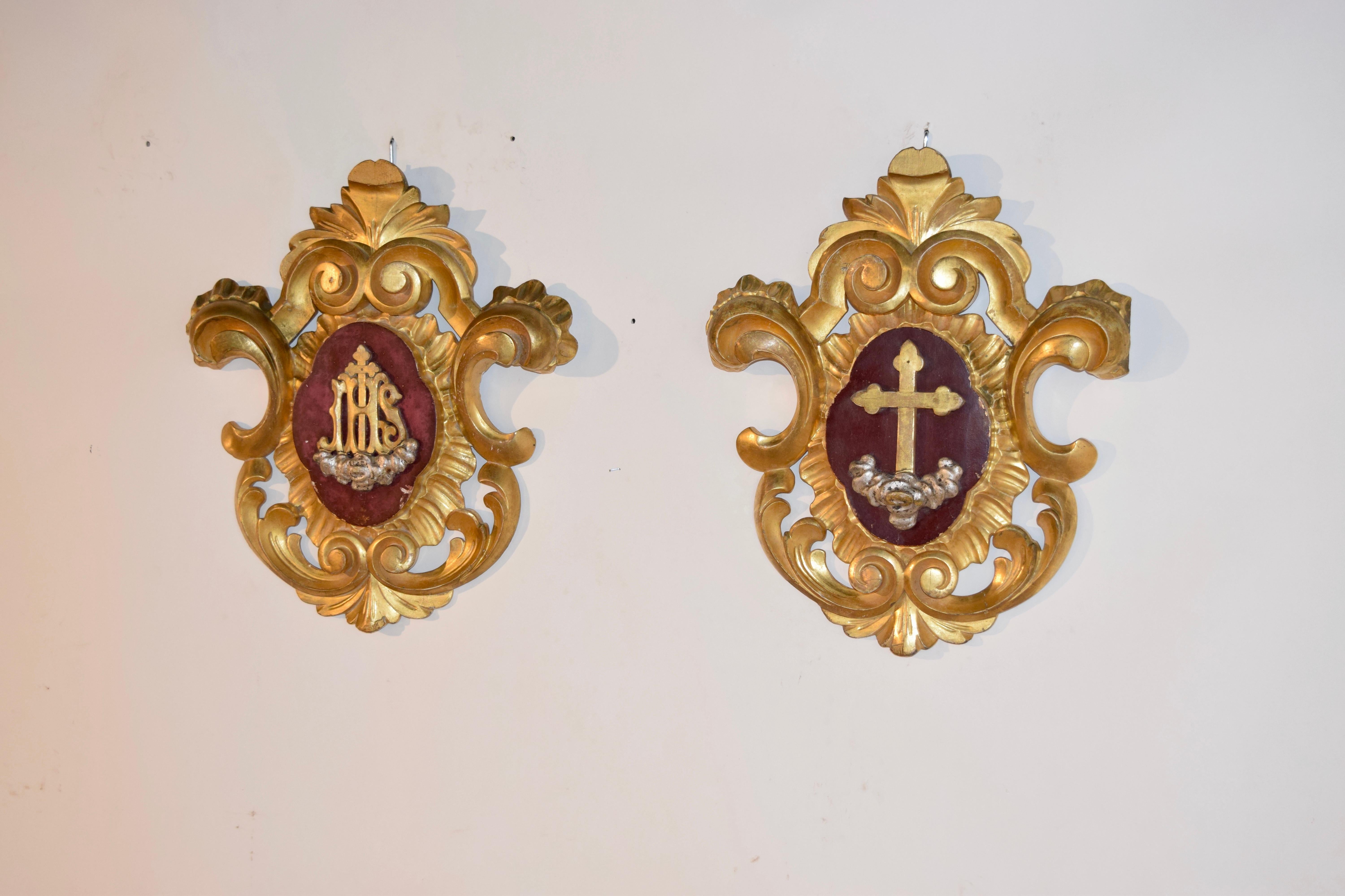 Pair of 19th century ecclesiastical plaques from France. They are hand carved from wood and gilded with central designs of a cross on one and IHS, the symbol of the Lord, on the other.