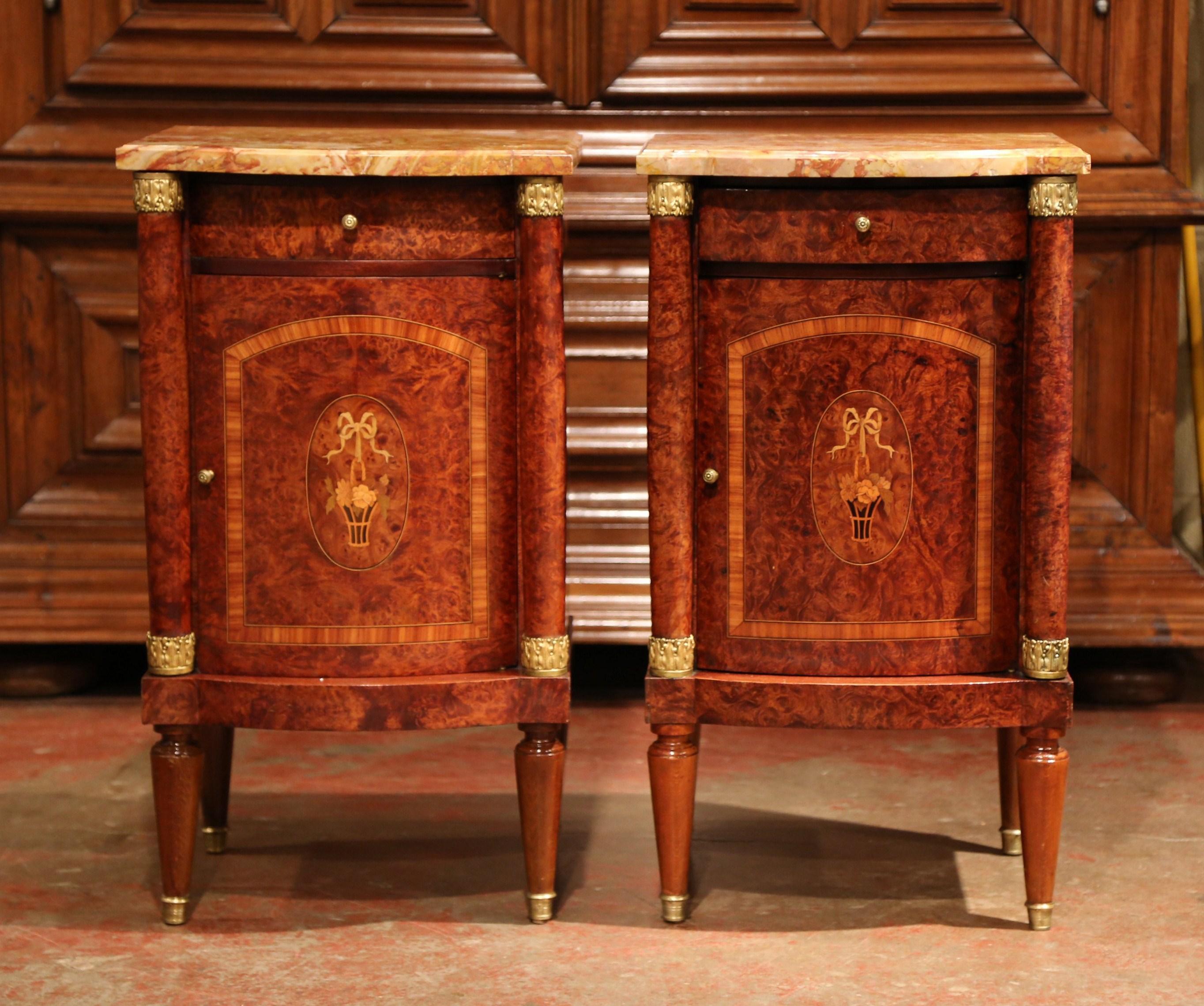 This elegant pair of antique fruitwood nightstands was created in France, circa 1890. Rectangular in shape, the burl walnut bedside tables sit on four tapered legs and feature a single drawer and a curved centre door. The doors are embellished with