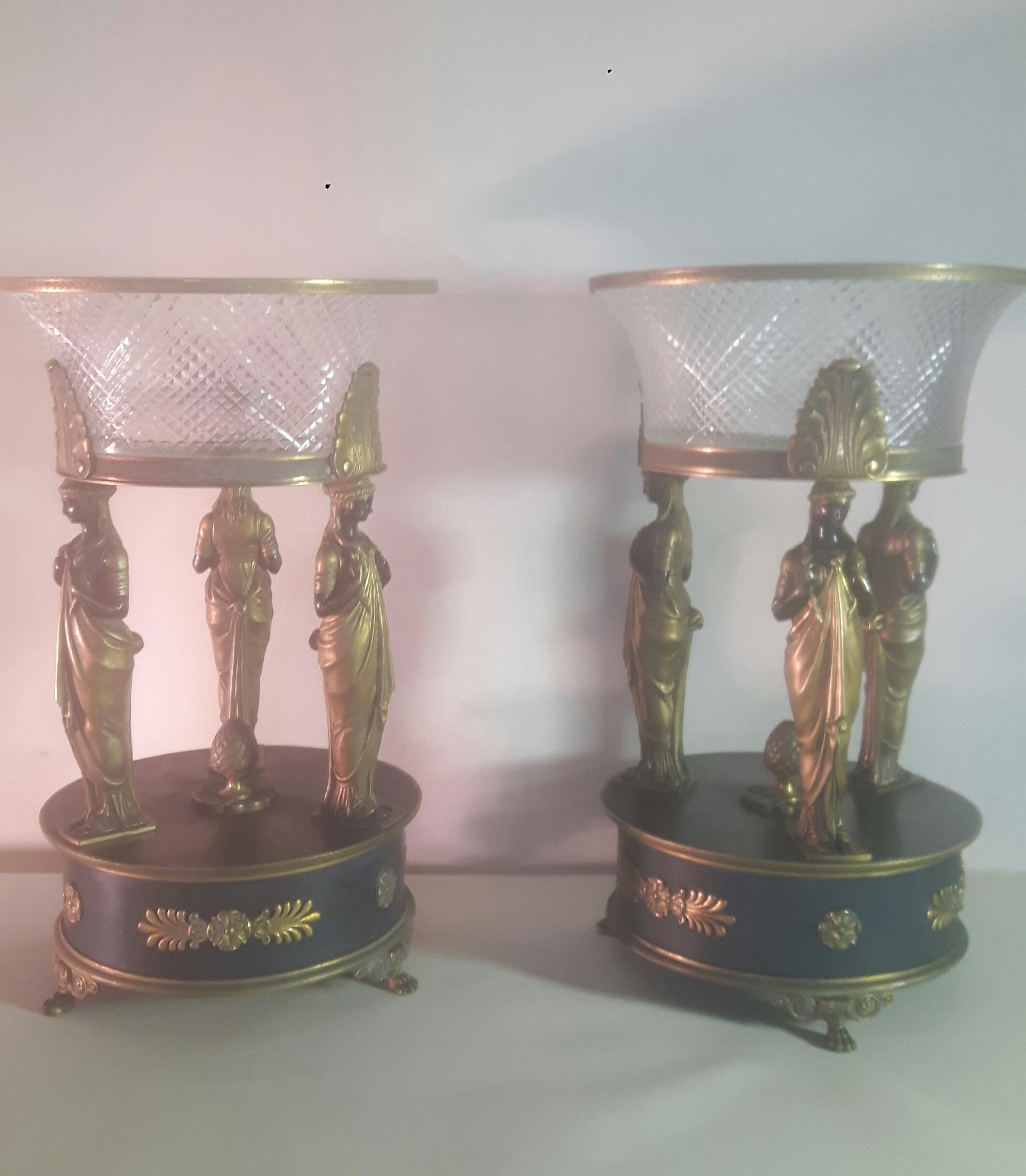 A fine large pair of 19th century French Empire bronze center pieces modeled as classical figures holding a loft acanthus capped crystal bowls.