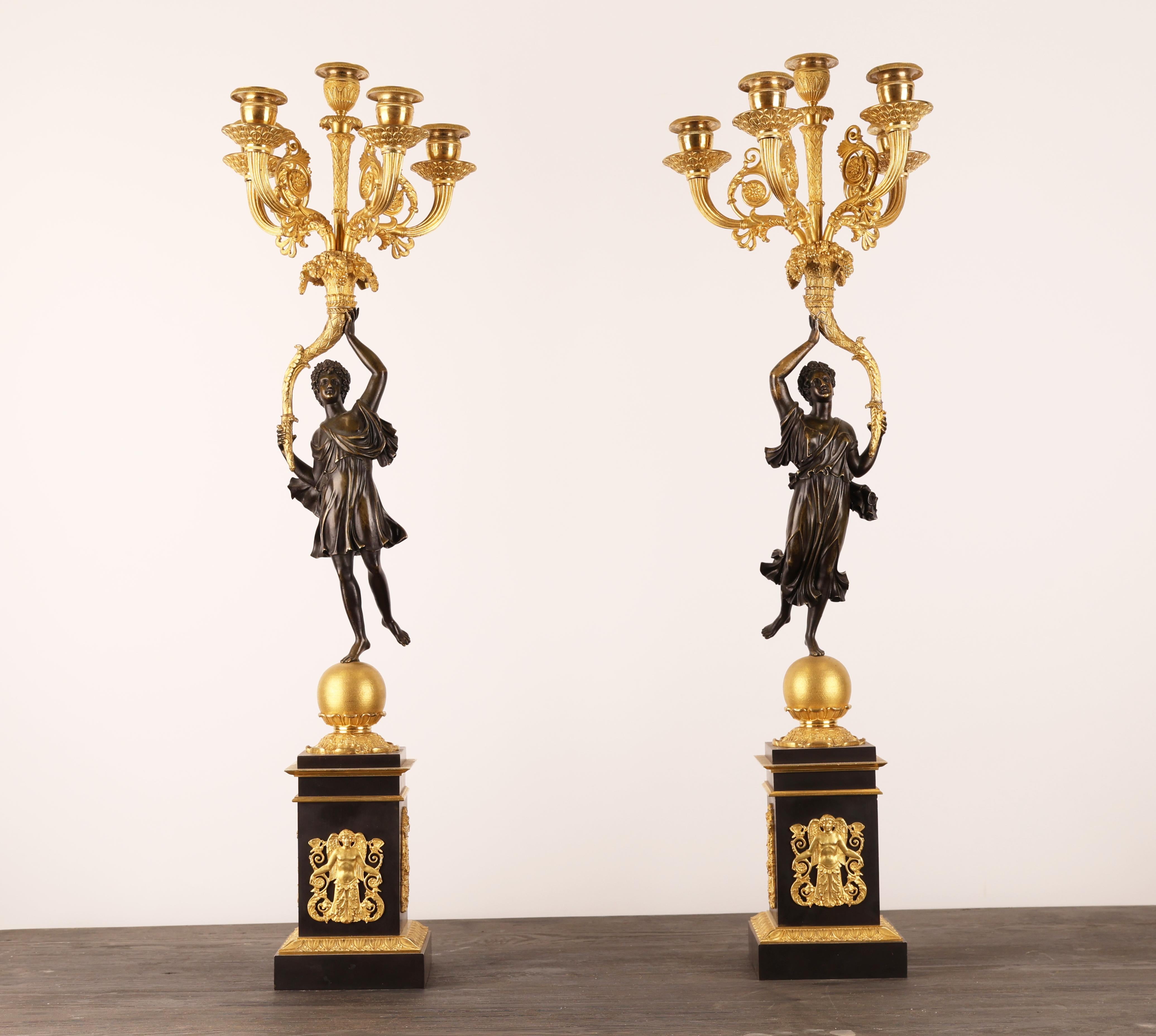 Una coppia di candelabri Impero per cinque candele ciascuno, realizzati da Pierre Chibout all'inizio del XIX secolo. I candelabri sono realizzati in bronzo patinato e dorato a fuoco. I candelabri presentano motivi di angeli.
