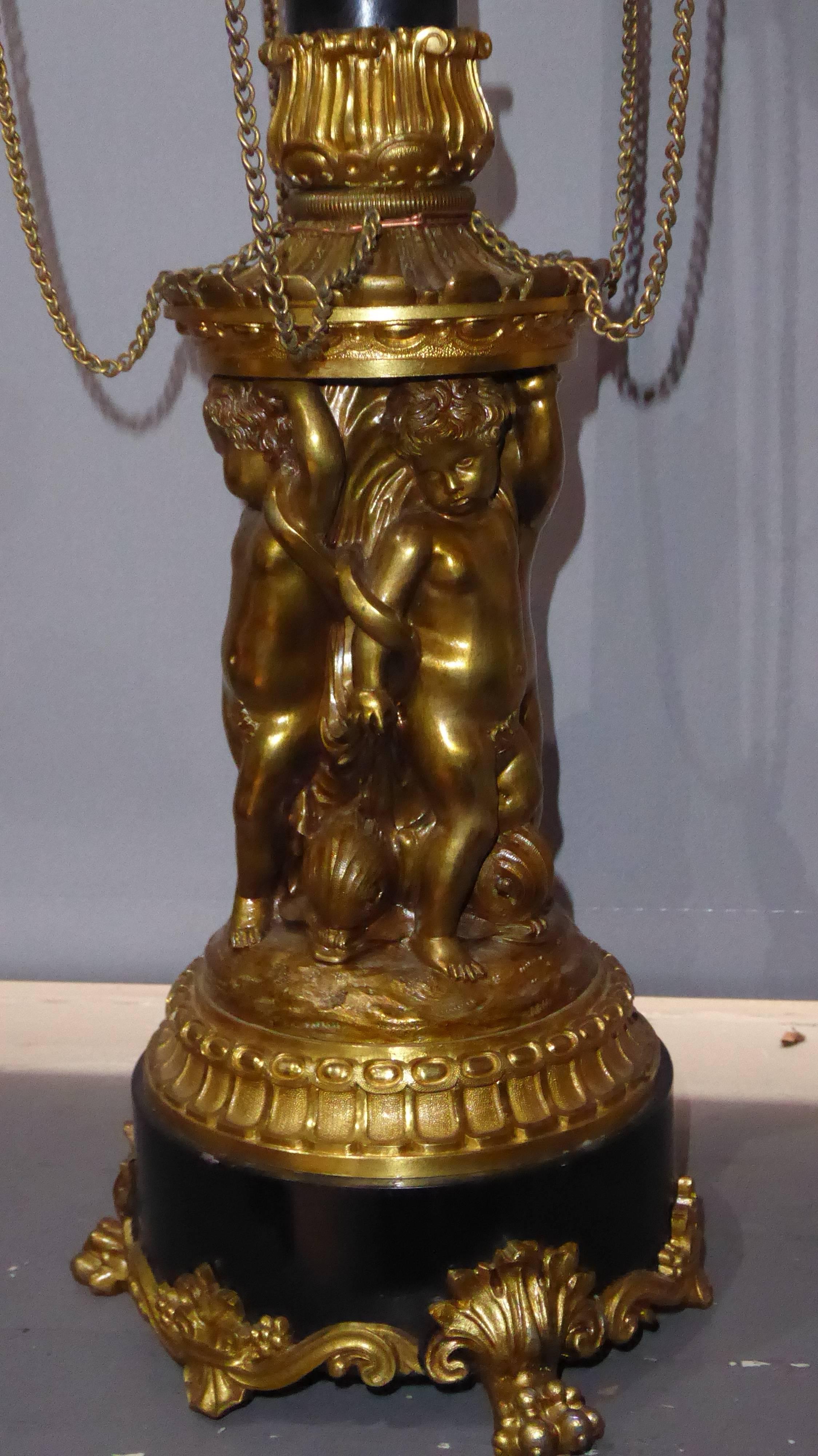 A fine pair of 19th century Empire gilt bronze five branch candelabra, the moulded sconces of oil lamp form, united by chains, support on a slate column held by four cherubs and diving Dolphins terminating on three lion paw feet.