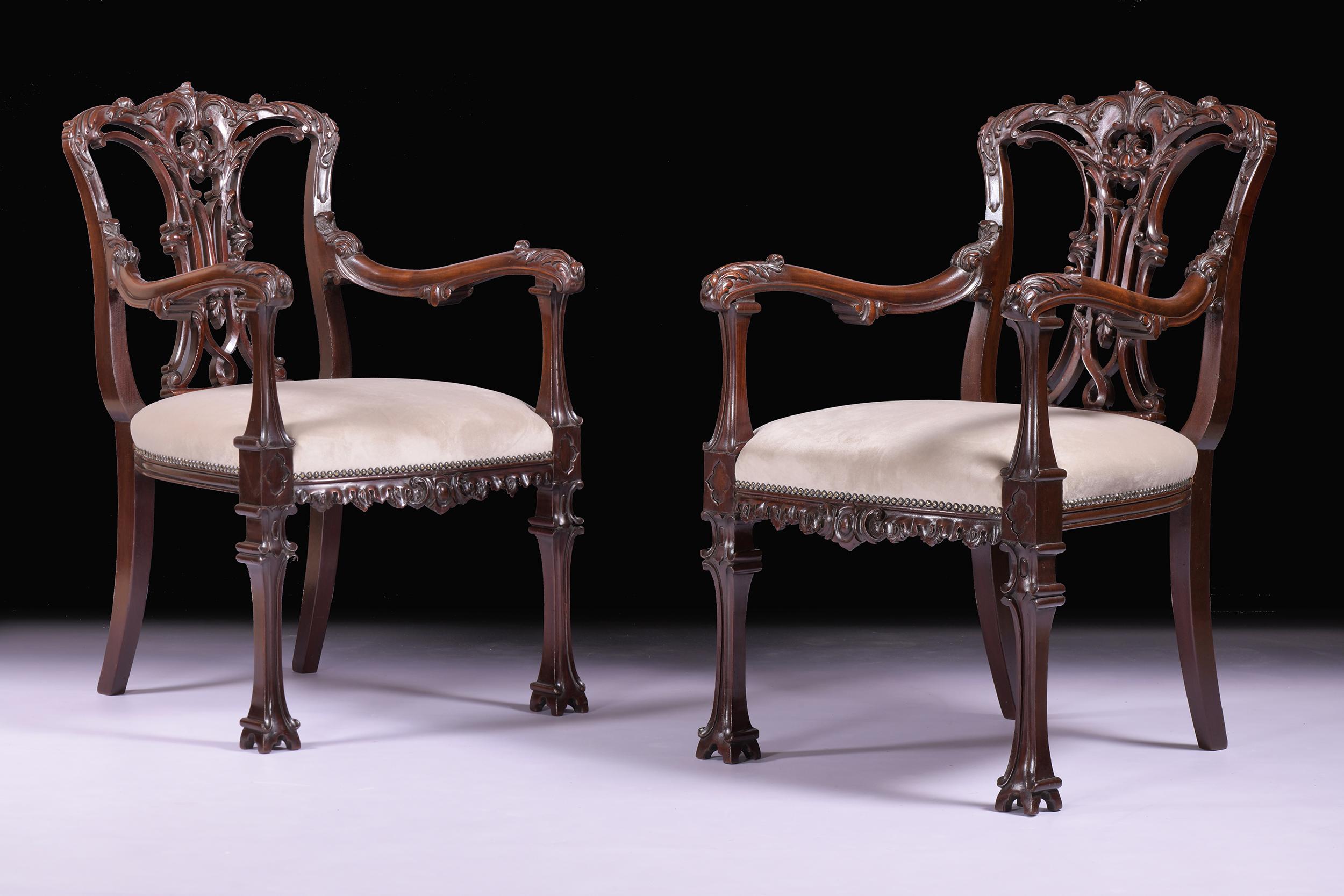Una bella coppia di poltrone del XIX secolo in stile Chippendale cinese, con la cresta a cupola sopra un'elaborata stecca a nastro intagliata e intrecciata, unite da un sedile imbottito e da braccioli a voluta, con le gambe anteriori che terminano