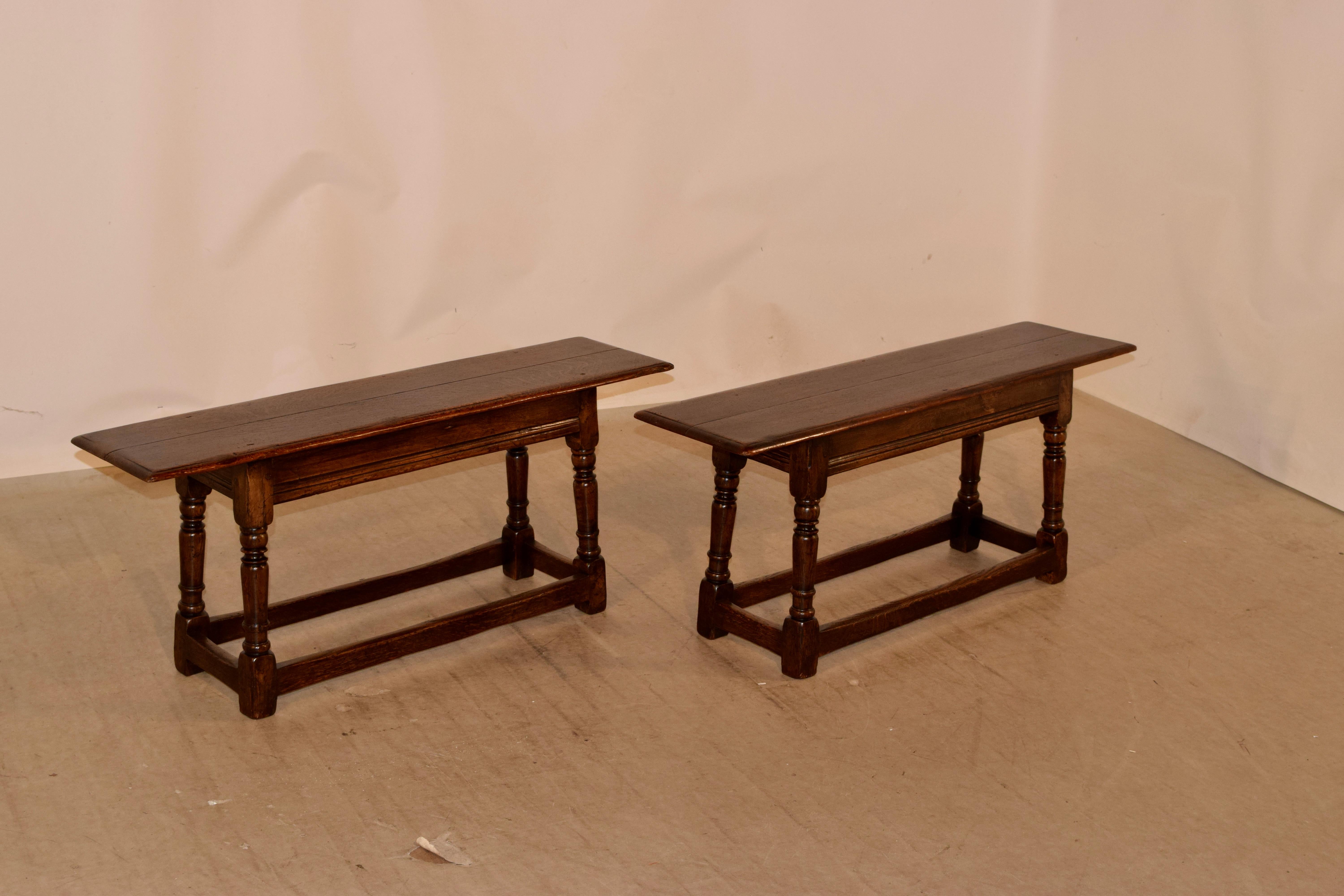 Pair of 19th century oak benches from England with two plank tops which have beveled edges and simple aprons, supported on hand turned and splayed legs, joined by simple stretchers.