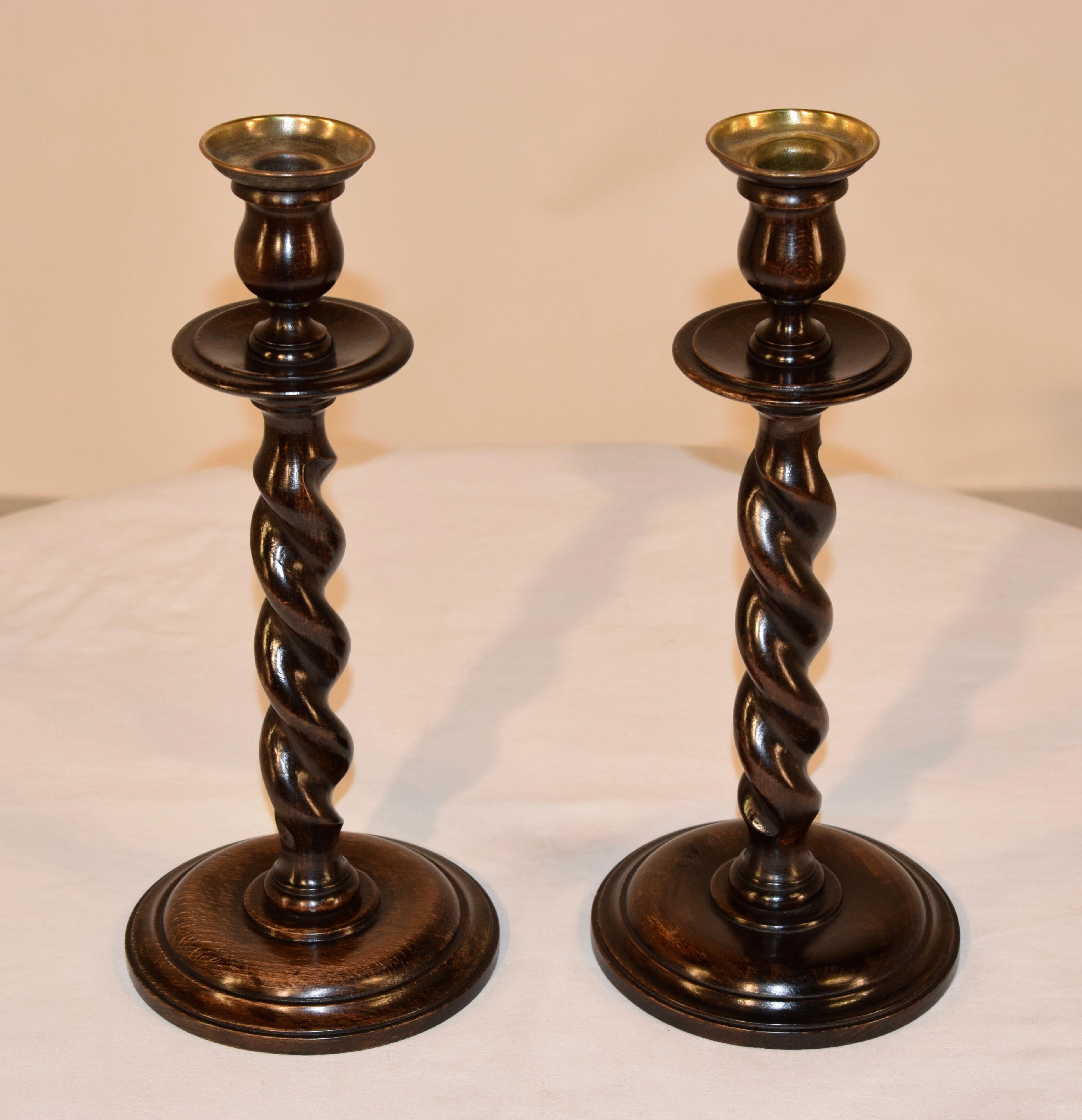 Pair of 19th century English oak candlesticks with hand-turned brass inserts and tulip shaped candle cups over hand-turned oak bobeches and hand-turned barley twist stems over hand-turned molded bases.