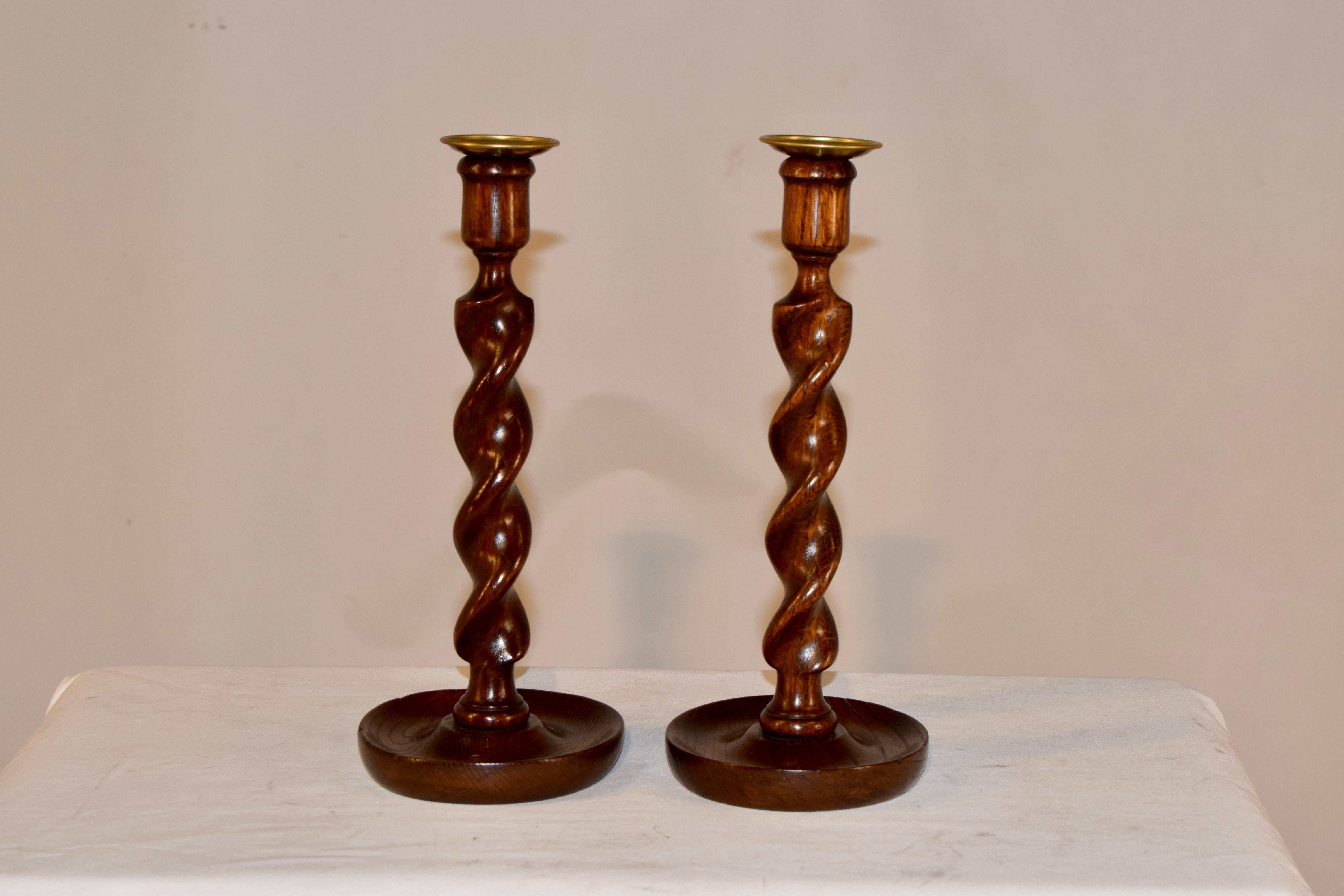 Pair of wonderfully decorative hand turned candlesticks made from oak. The candle cups are replaced with hand turned brass candle cups, which we had made in England. The hand turned barley twist stems are lovely and are supported on hand turned fish