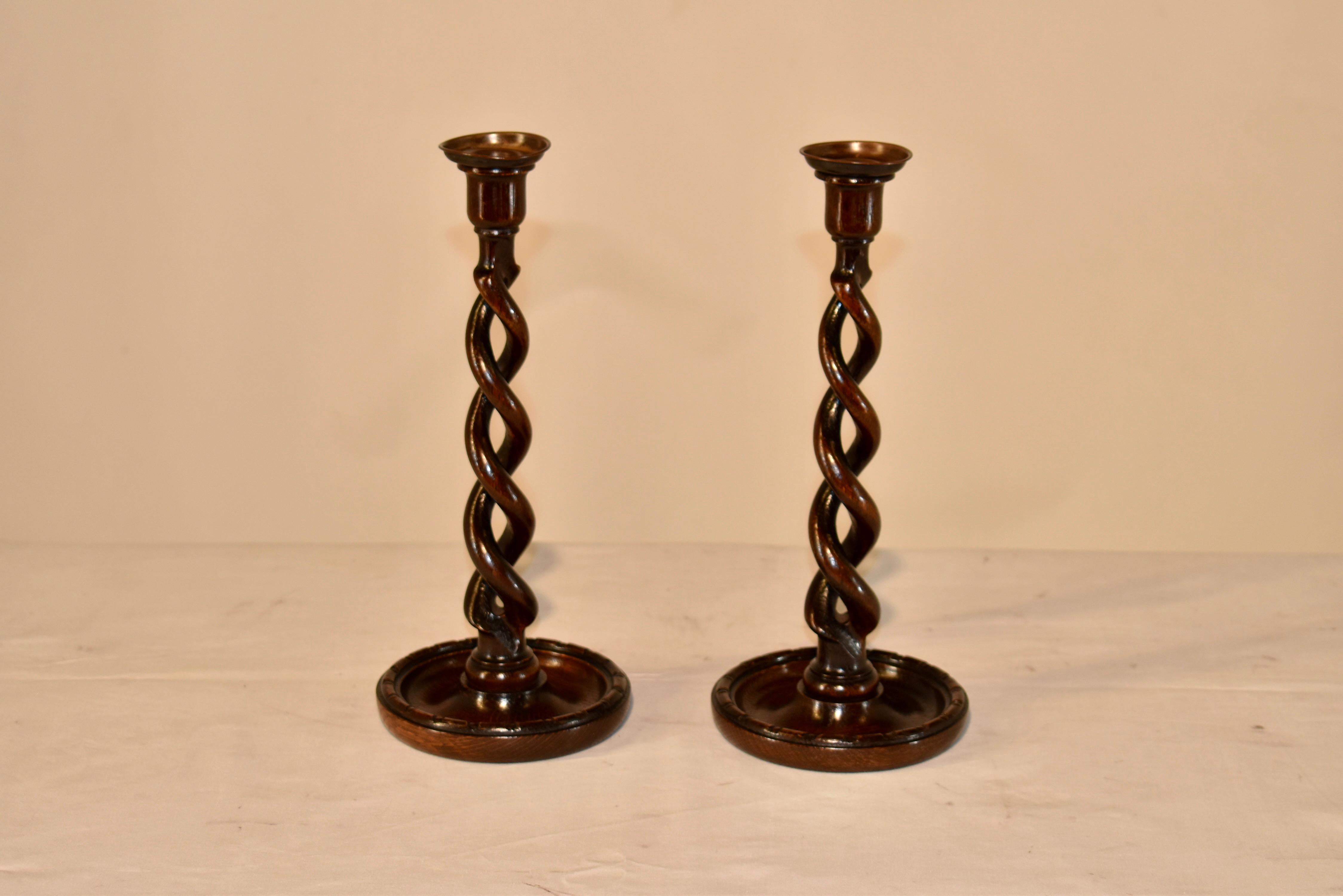 Pair of 19th century oak candlesticks from England with brass bobeches at the top, following down to turned candle cups over hand turned open barley twist stems. The candlesticks are supported on hand turned dish shaped bases with hand beading for