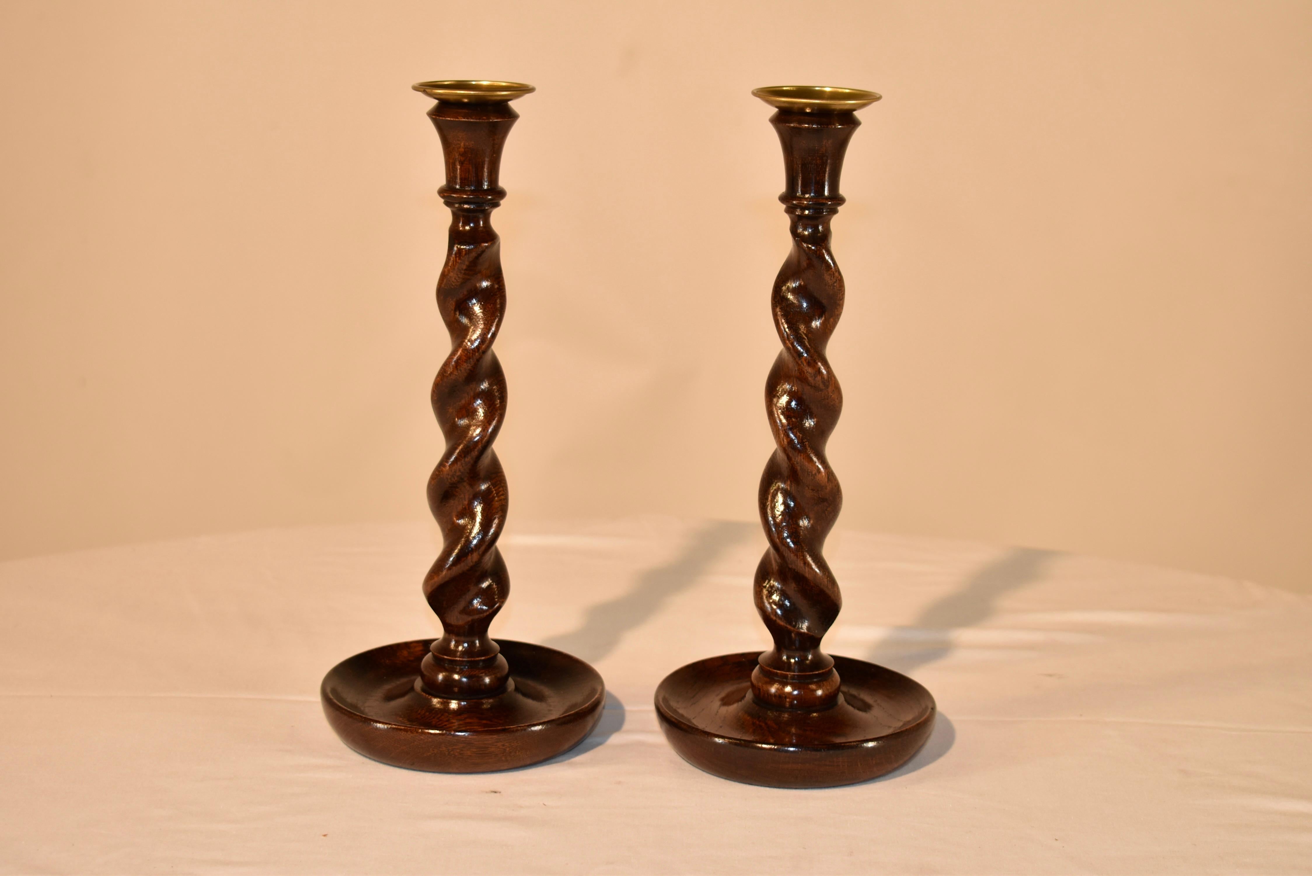 Pair of late 19th century oak candlesticks from England with hand turned candle cups, supported on top of hand turned barley twist stems and resting on hand turned dish shaped bases.