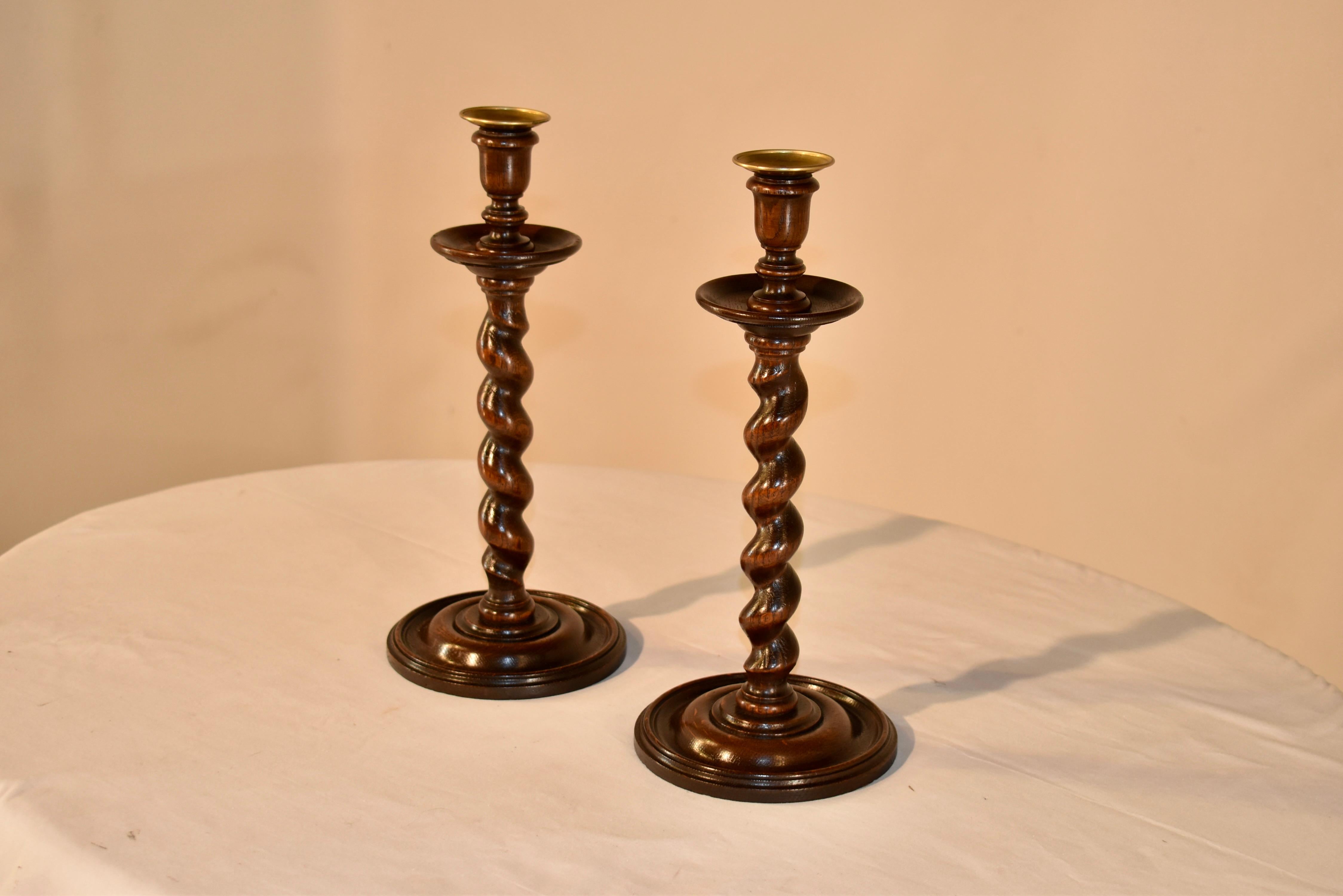 Pair of 19th century oak candlesticks from England with brass inserts inside hand turned candle cups over wonderfully large bobeches and supported on hand turned barley twist stems over hand turned and molded bases. Wonderfully tall at 14 inches in