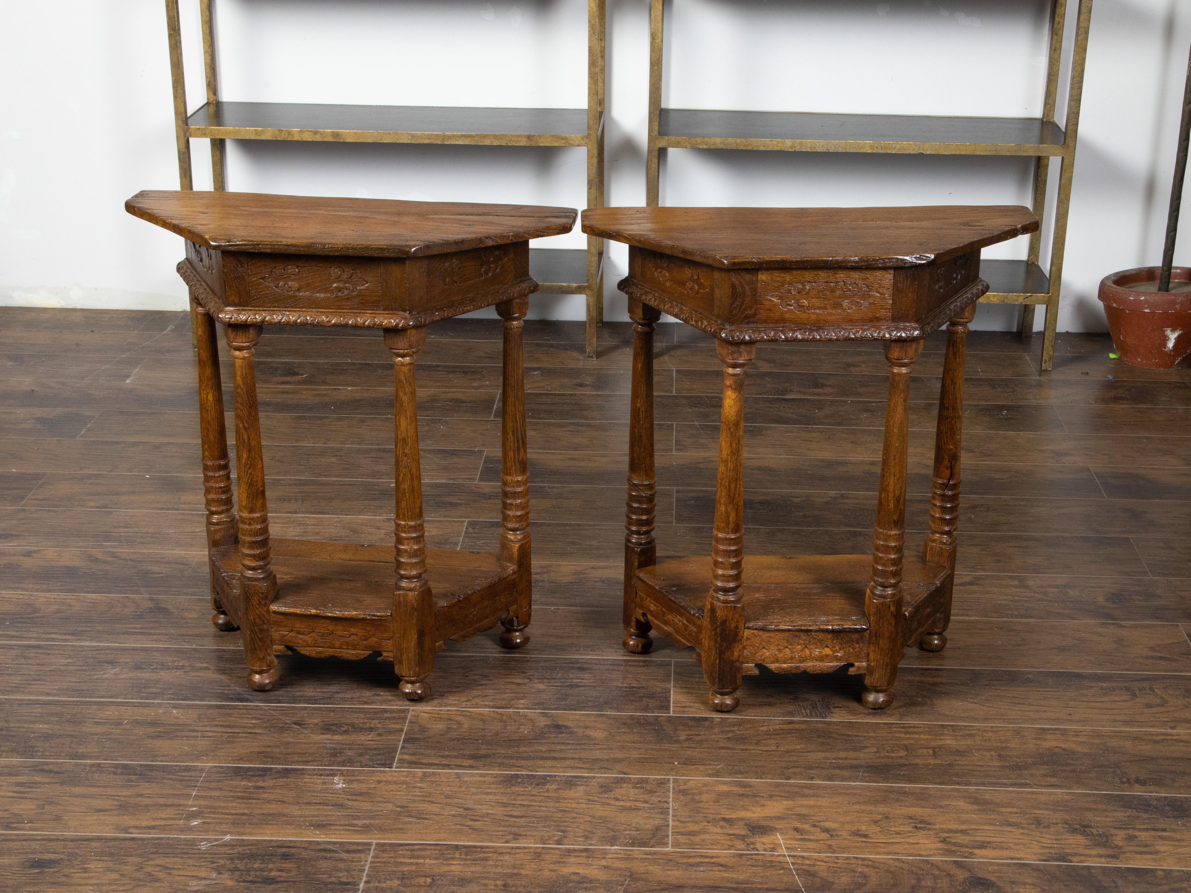 A pair of English oak demilune tables from the 19th century, with polygonal tops, carved aprons and turned legs. Created in England during the 19th century, each of this pair of oak demilunes features a polygonal top sitting above a carved apron.