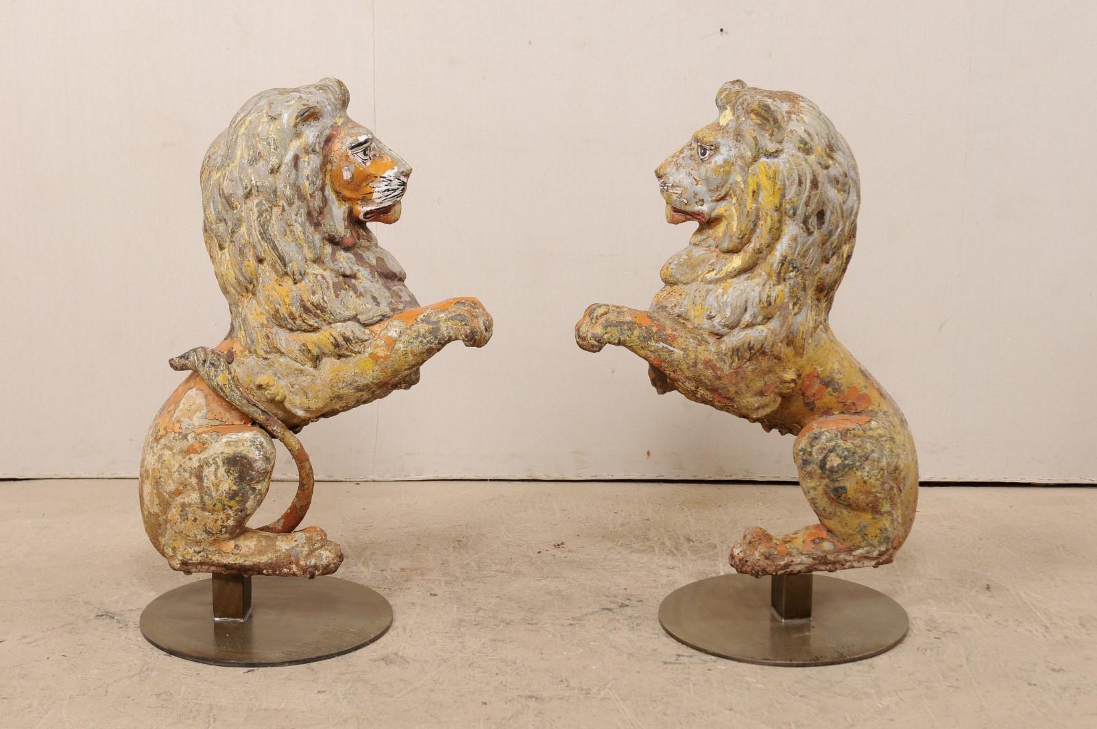 A pair of English lions of cast-iron from the 19th century on stands. This antique pair of cast-iron lions from England are each one half of a pair, with front position being shown at side to create a perfectly seated pair, which have then been