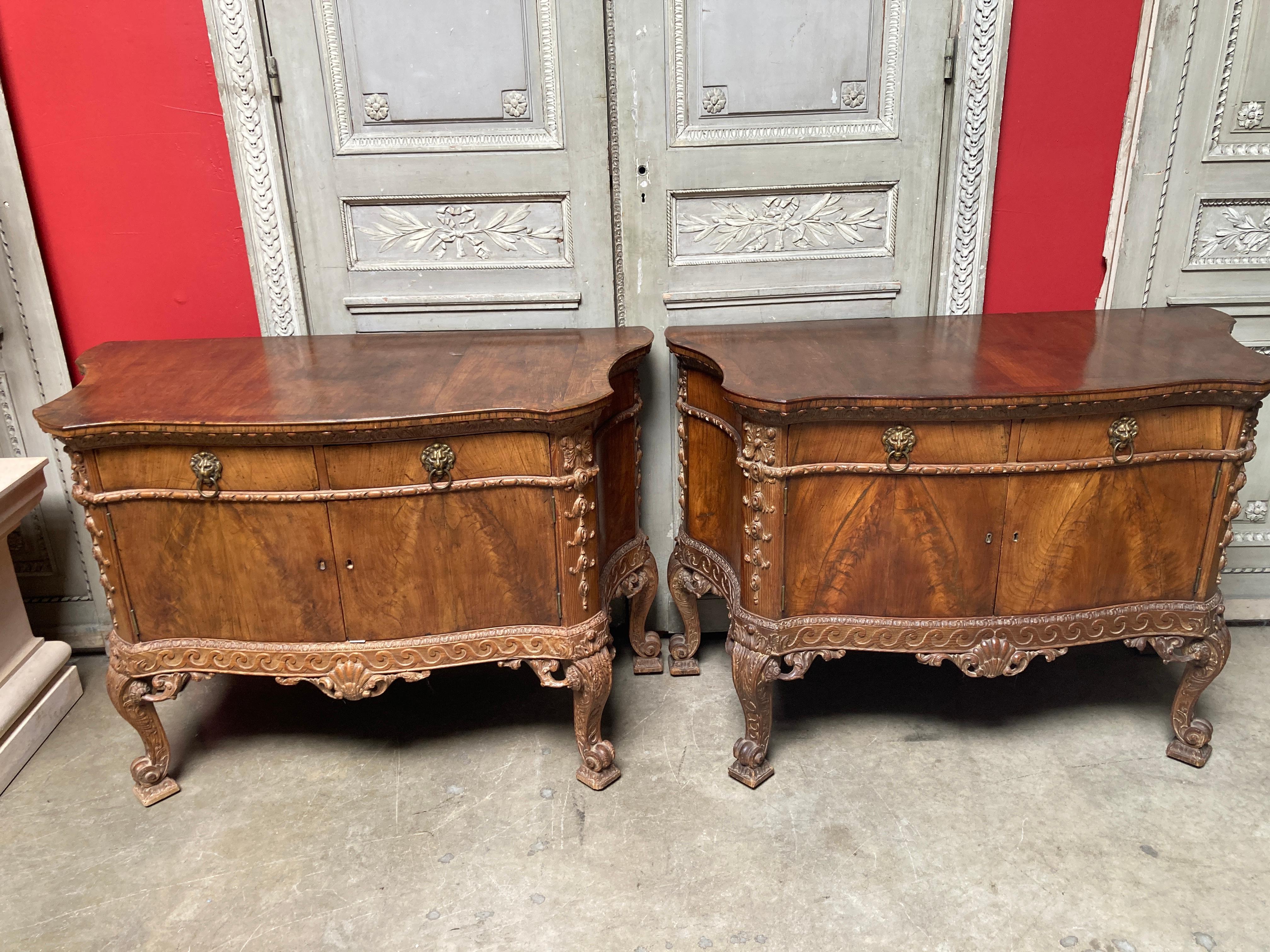 A pair of English George II style cabinets in burled walnut and pine from the 19th century. 
The pair of nicely carved cabinets have cabriole legs and have of two drawers and doors each.