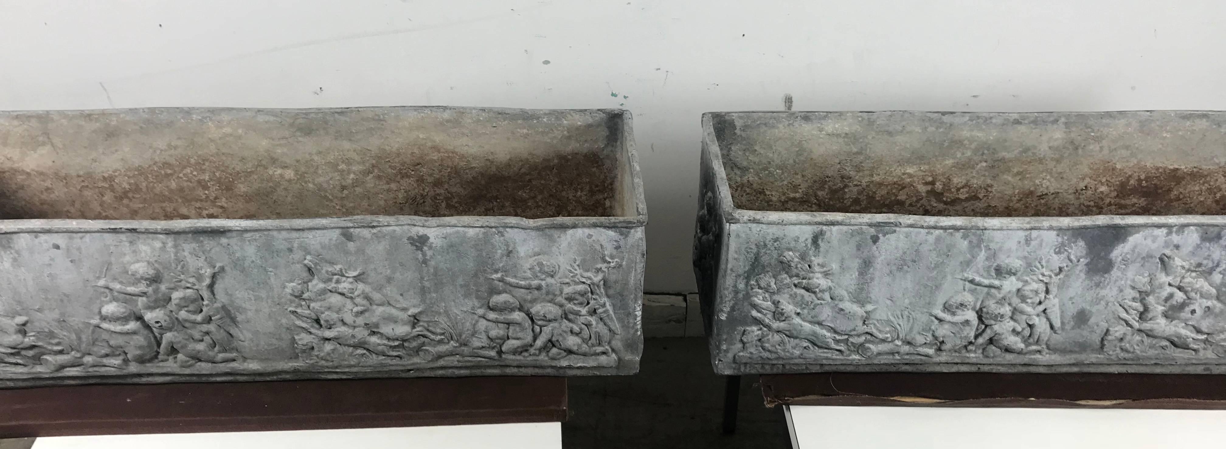 Matched pair of lead planters with figural detail on all sides of classic relief depicting angels and animal motif. Generous size and gorgeous presence. Extremely heavy, drainage holes. Hand delivery avail to New York City or anywhere en route from