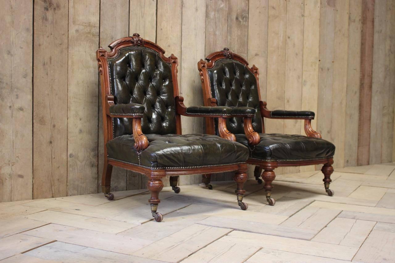 A smart pair of mid-19th century English library chairs in dark green buttoned leather with brass castors.