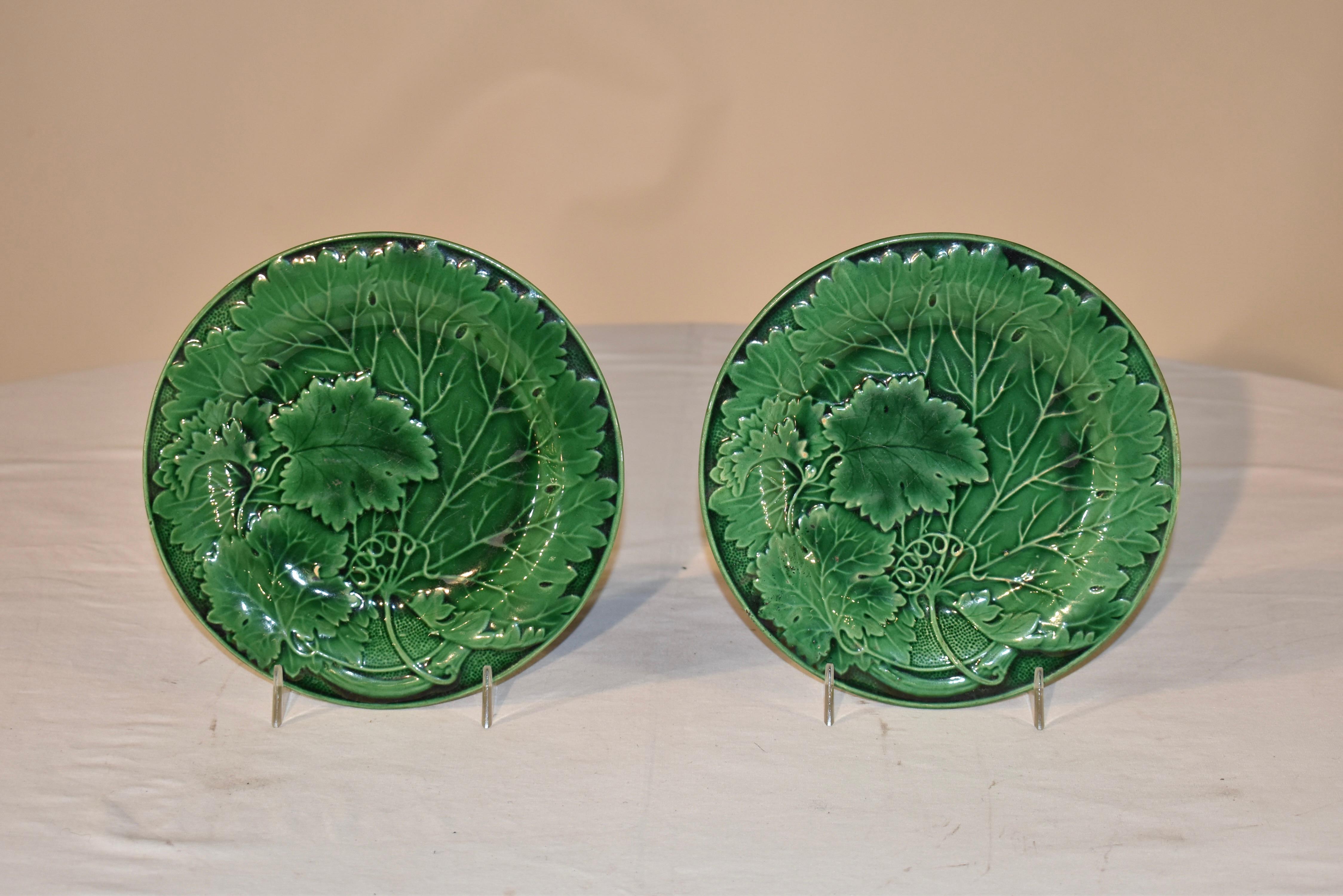 Pair of lovely 19th century English majolica plates in green. The pattern is a large single leaf with smaller leaves overlapping and stippling along a molded border edge. Plate stands not included.