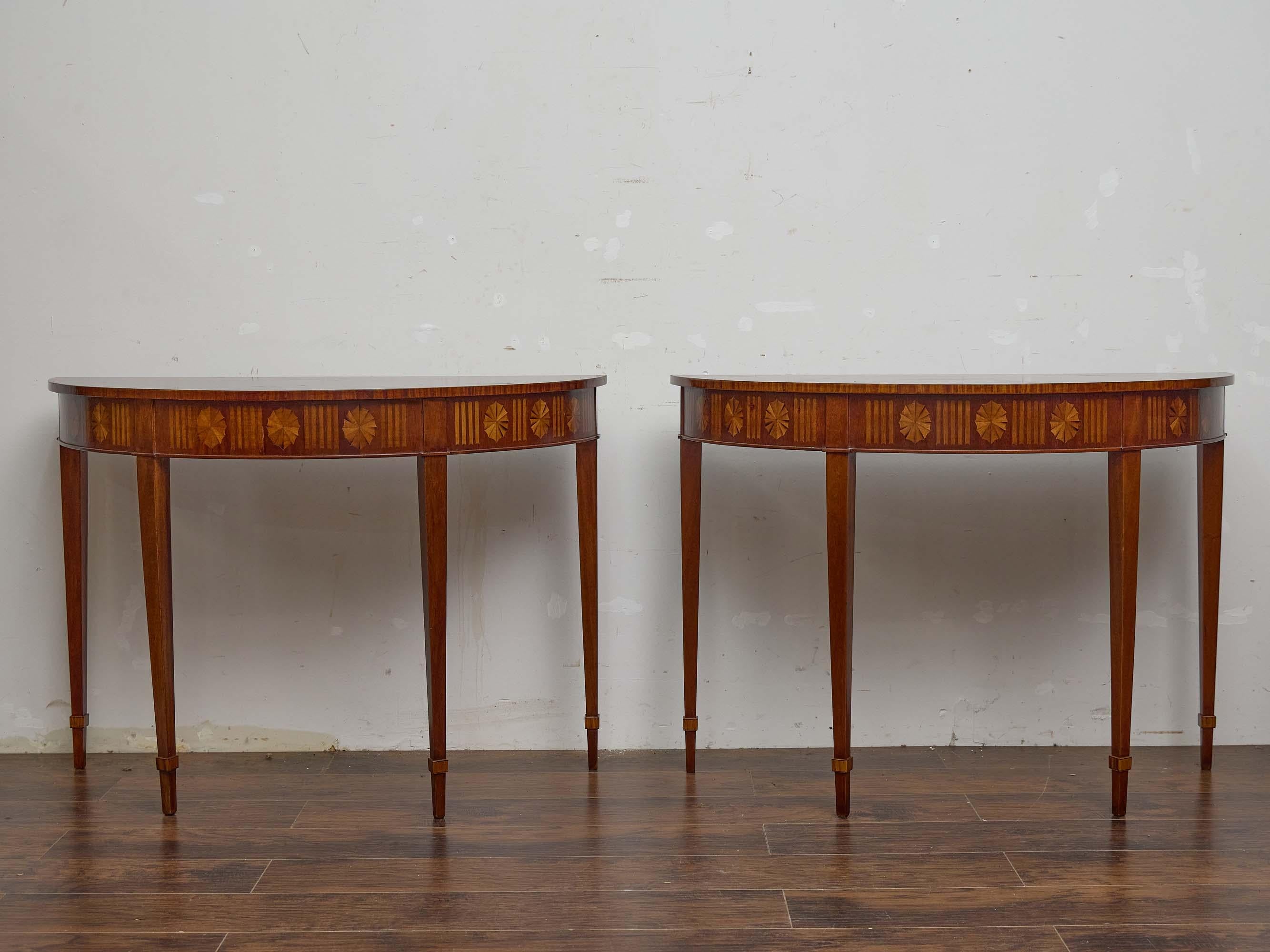 Une belle paire de consoles demi-lune anglaises du XIXe siècle en acajou, fabriquées dans le style néoclassique et faisant écho à l'élégance de la tradition Sheraton et Regency. Les plateaux présentent de fins motifs d'éventail plaqués rayonnant à