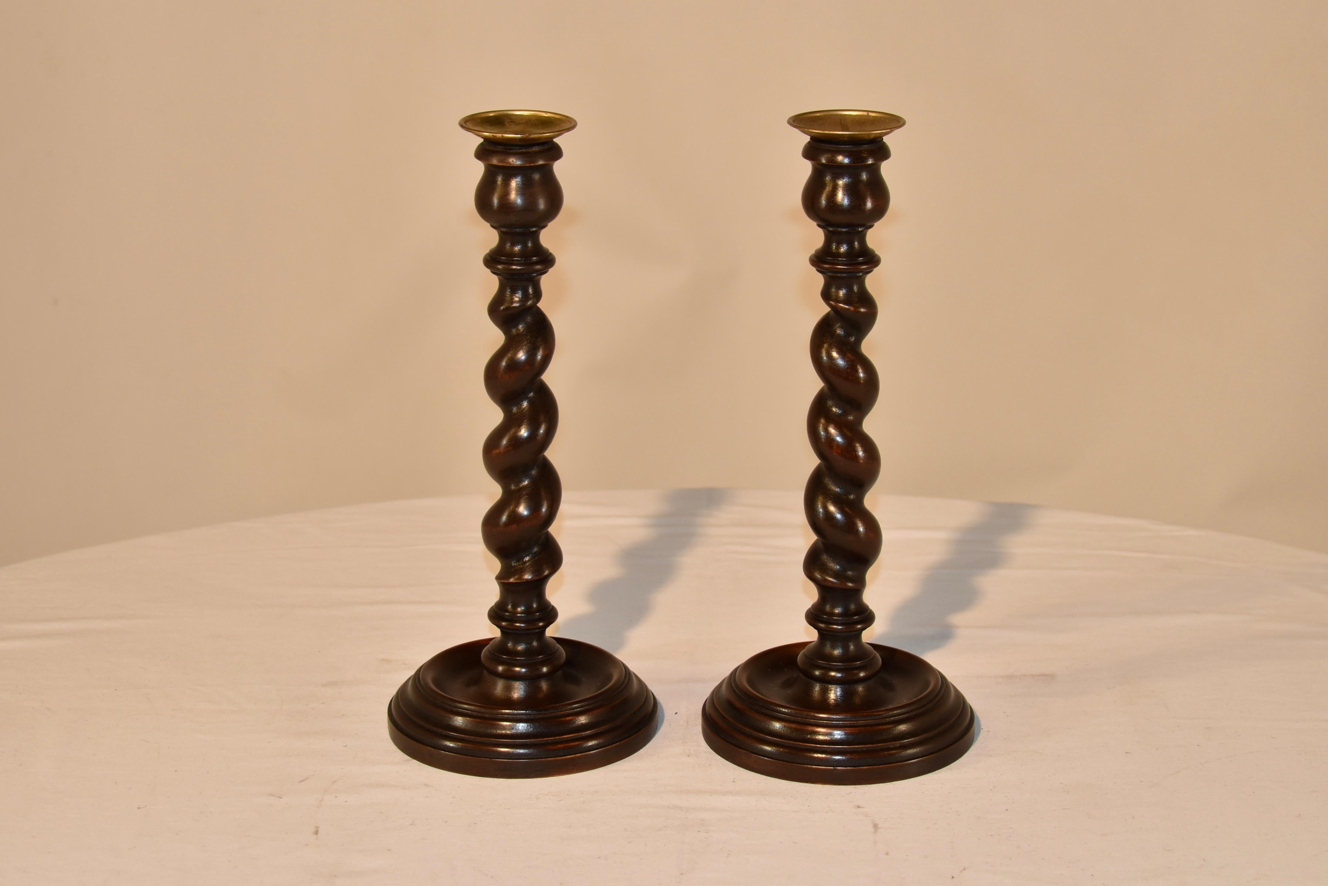 Pair of exquisite 19th century oak candlesticks from England with hand turned brass bobeches over tulip turned candle cups. The stems are hand turned barley twist and are supported on hand turned bases with lovely detail.