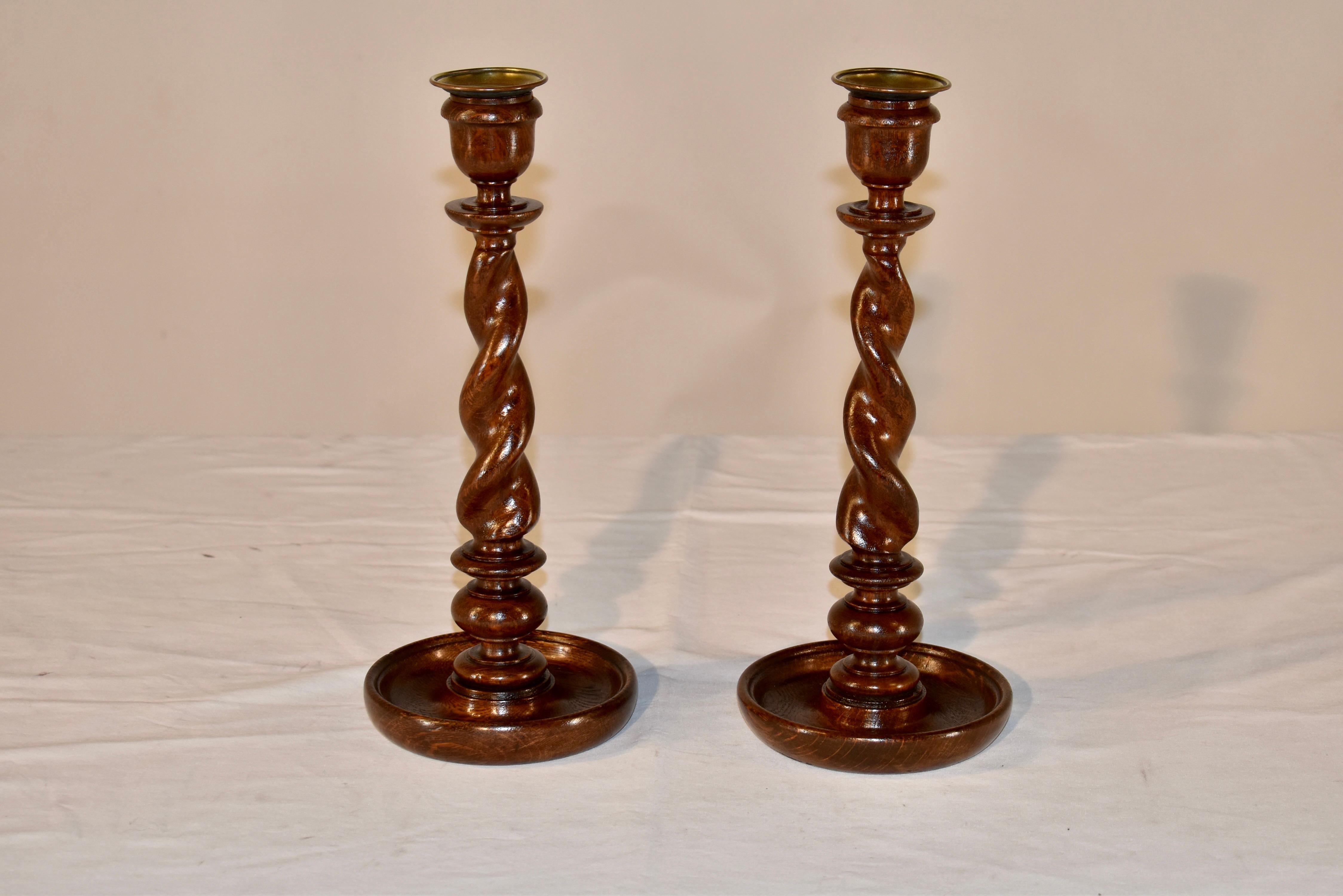 Pair of 19th century English oak candlesticks with hand turned candle cups over bobeches, supported on hand turned barley twist stems. The bases are hand turned dish shaped. This is a pair of wonderfully tall sticks in a gorgeous form.