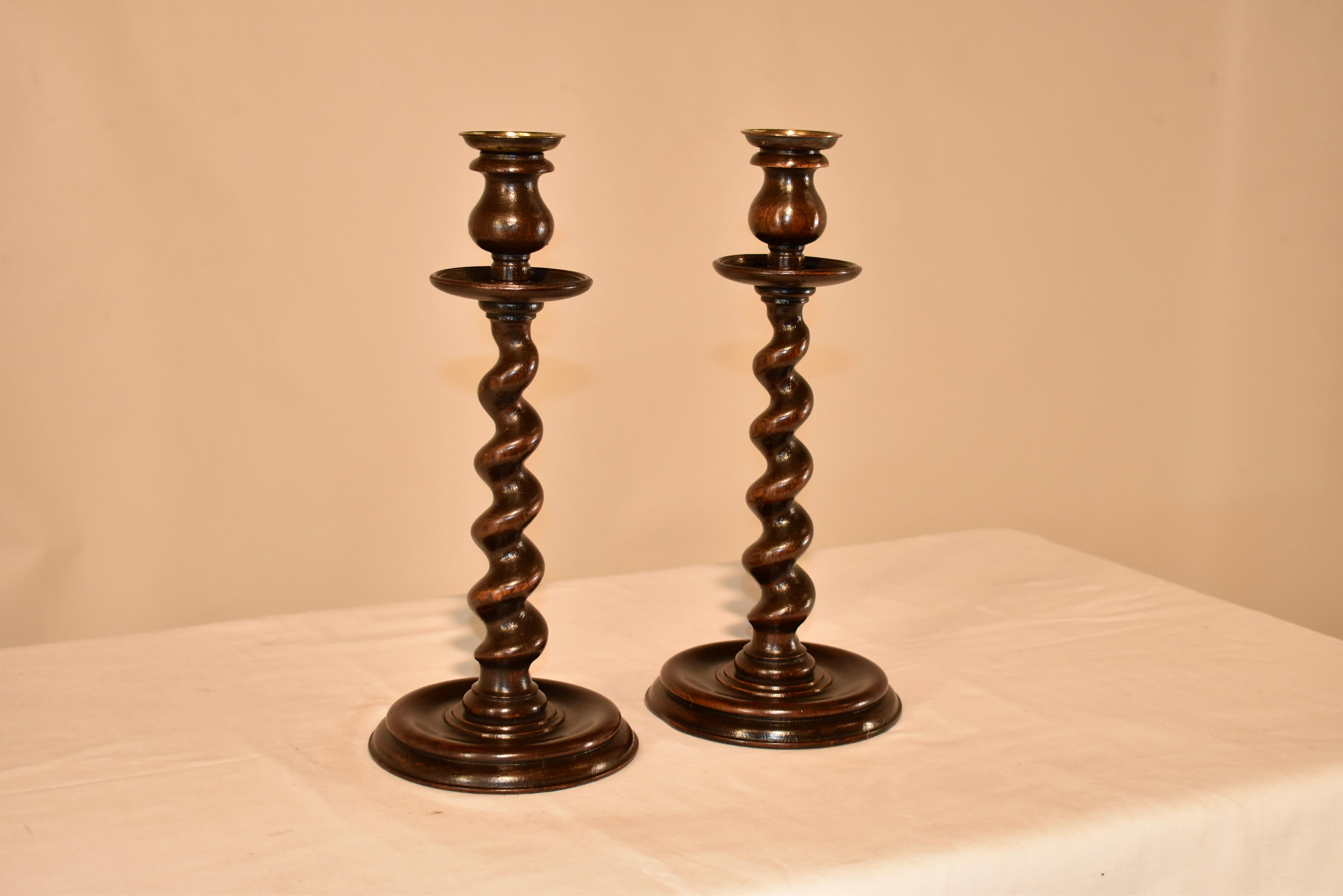 Pair of 19th century oak candlesticks from England. This wonderful pair of candlesticks have gorgeous tulip shaped turned candle cups, which have hand turned brass bobeches. The candle cups are over large hand turned wooden bobeches for an elegant
