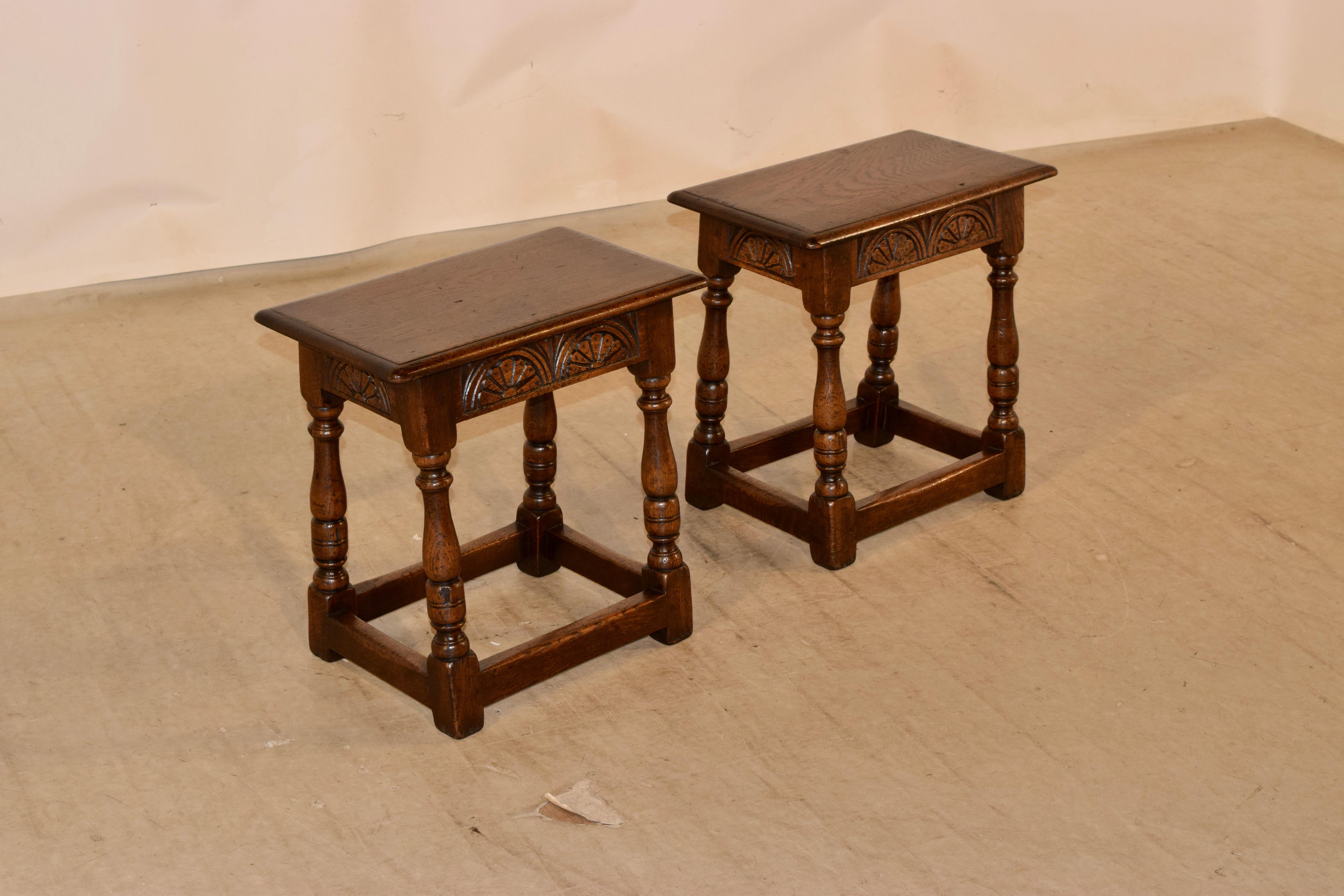 Pair of 19th century oak joint stools from England with a beveled edge around the top, following down to hand carved lunettes on the decorated aprons, and supported on splayed hand turned legs, joined by simple stretchers.