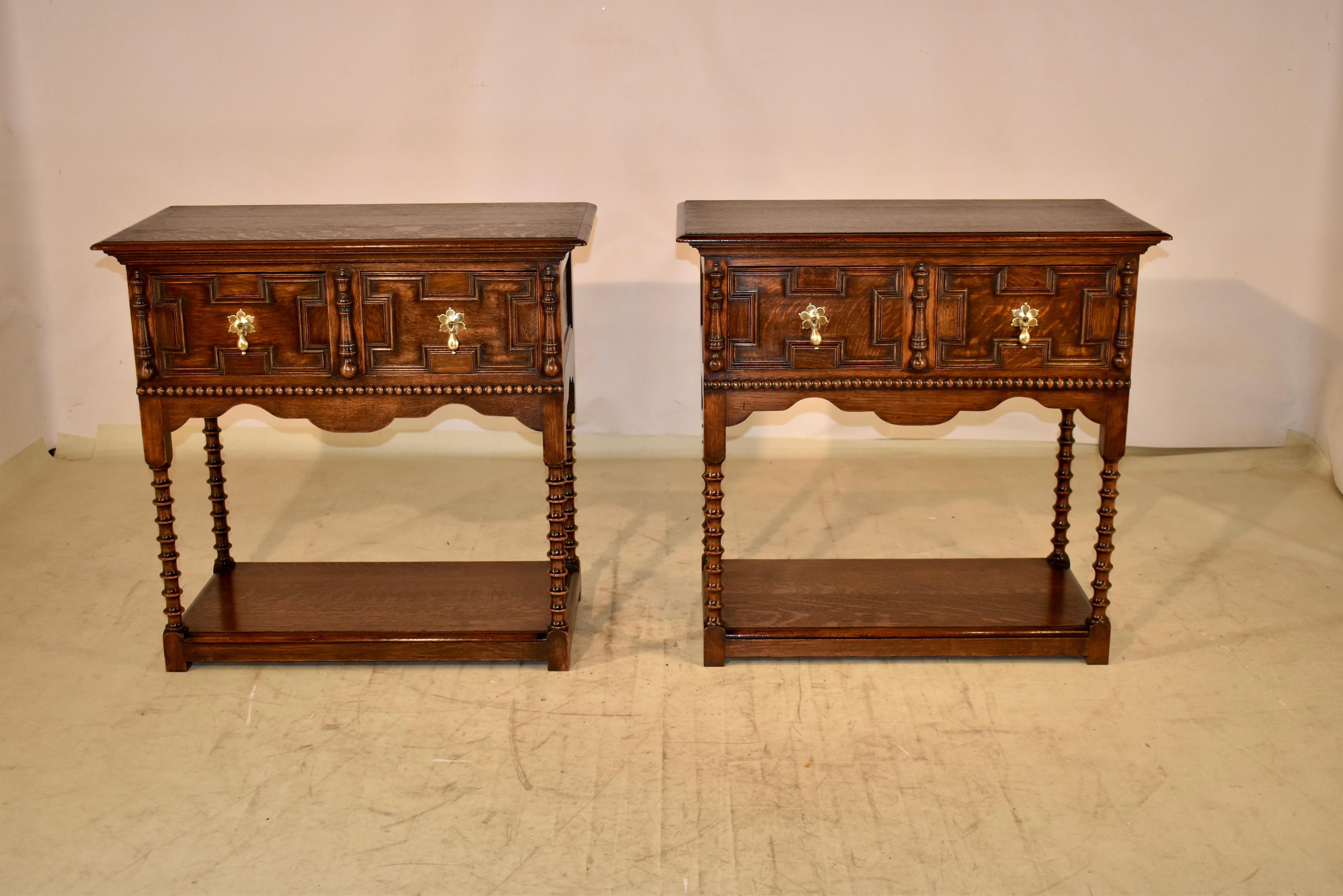 Pair of 19th century oak sideboards from England.  The tops are of pegged construction and have beveled edges.  The tops follow down to paneled sides and two geometrically paneled drawers in the front.  The drawers are flanked with applied turnings