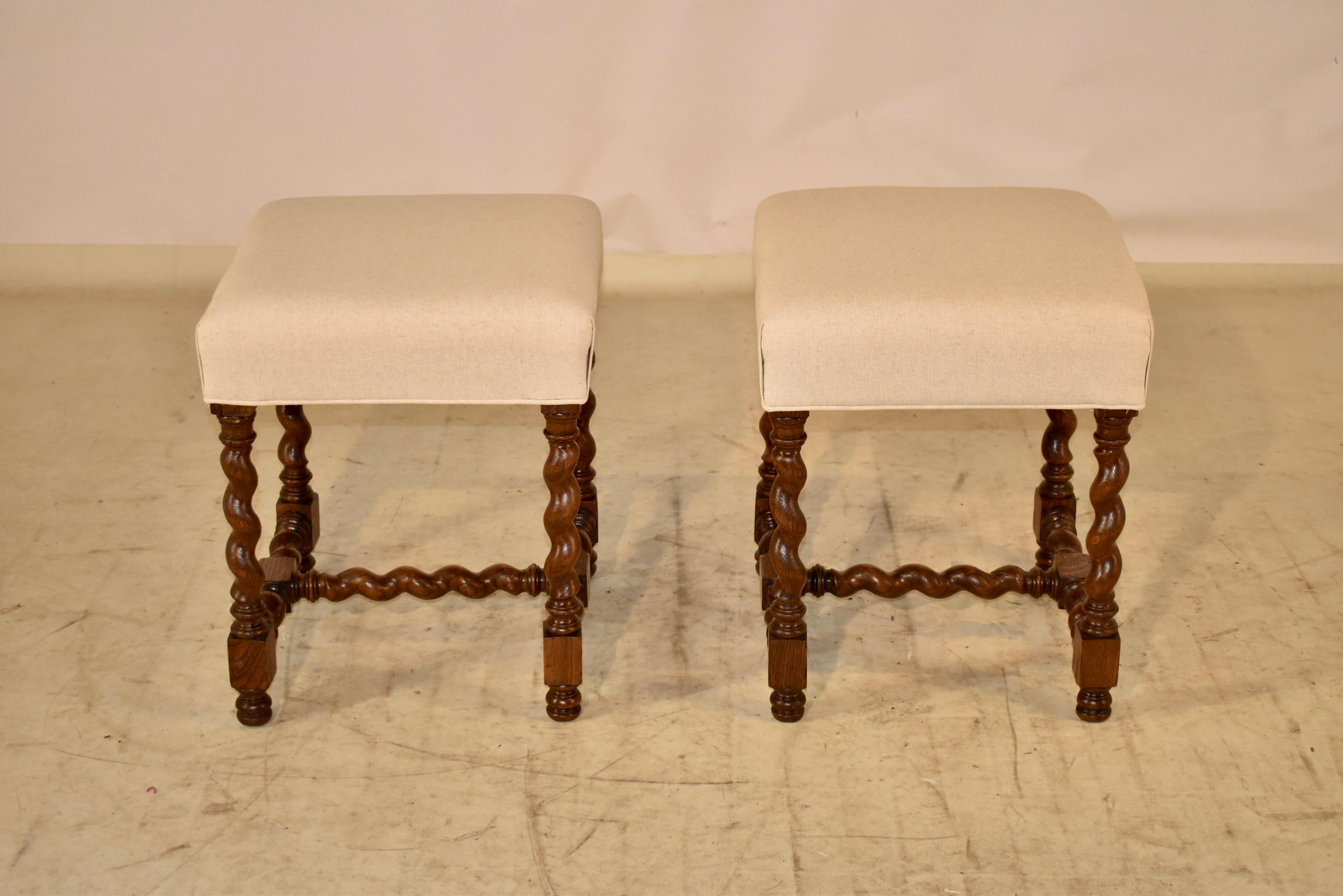 Lovely pair of 19th century oak stools from France with newly upholstered seats in linen. The bases are made from oak and have gorgeous hand turned barley twist legs, joined by a matching stretcher. Supported on hand turned feet.