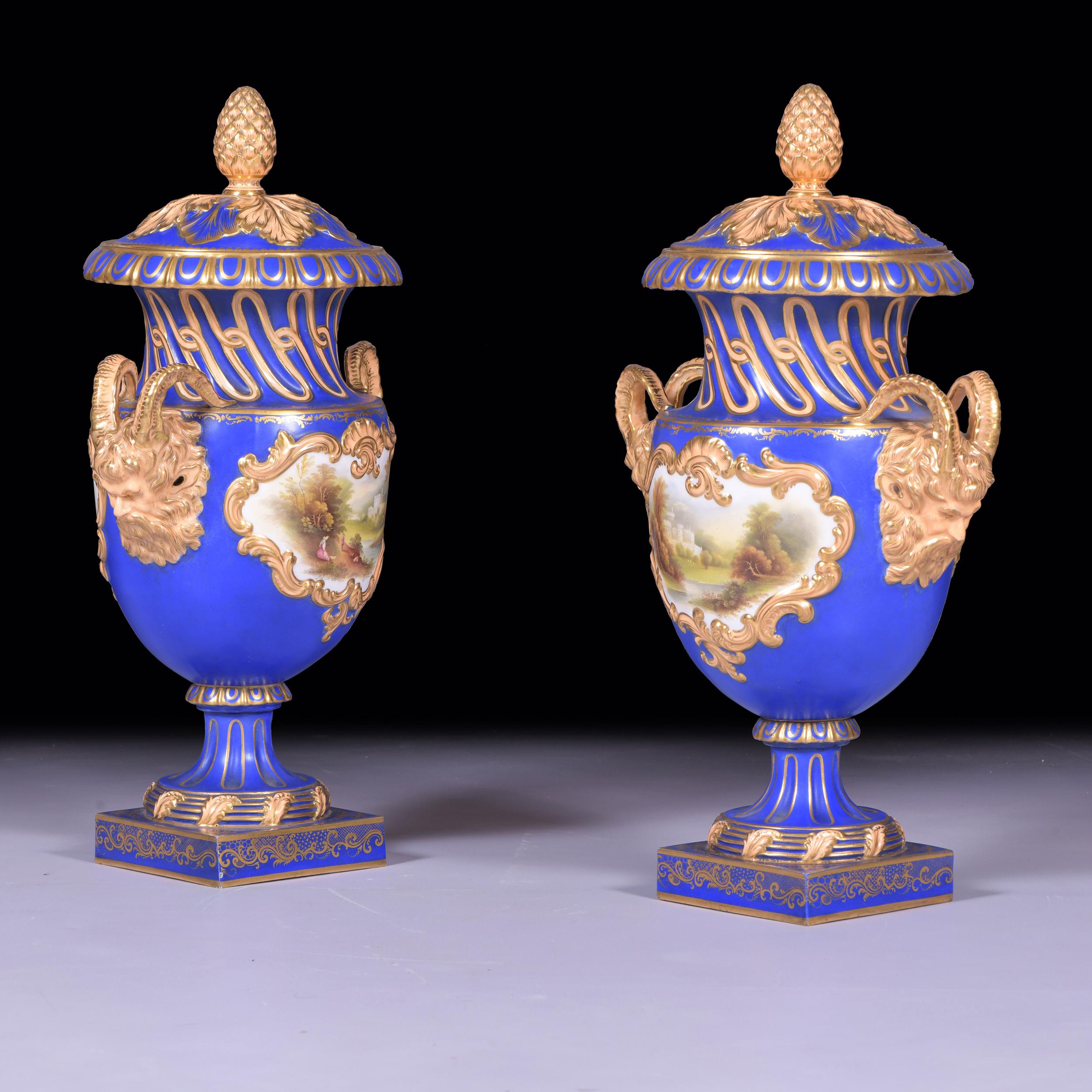Coppia di vasi e coperchi Coalport molto belli e attraenti, dipinti su un lato con pannelli di scene idilliache di castelli e sull'altro con un pannello di fiori colorati, i manici ben modellati con maschere e terminali decorati in oro, gli