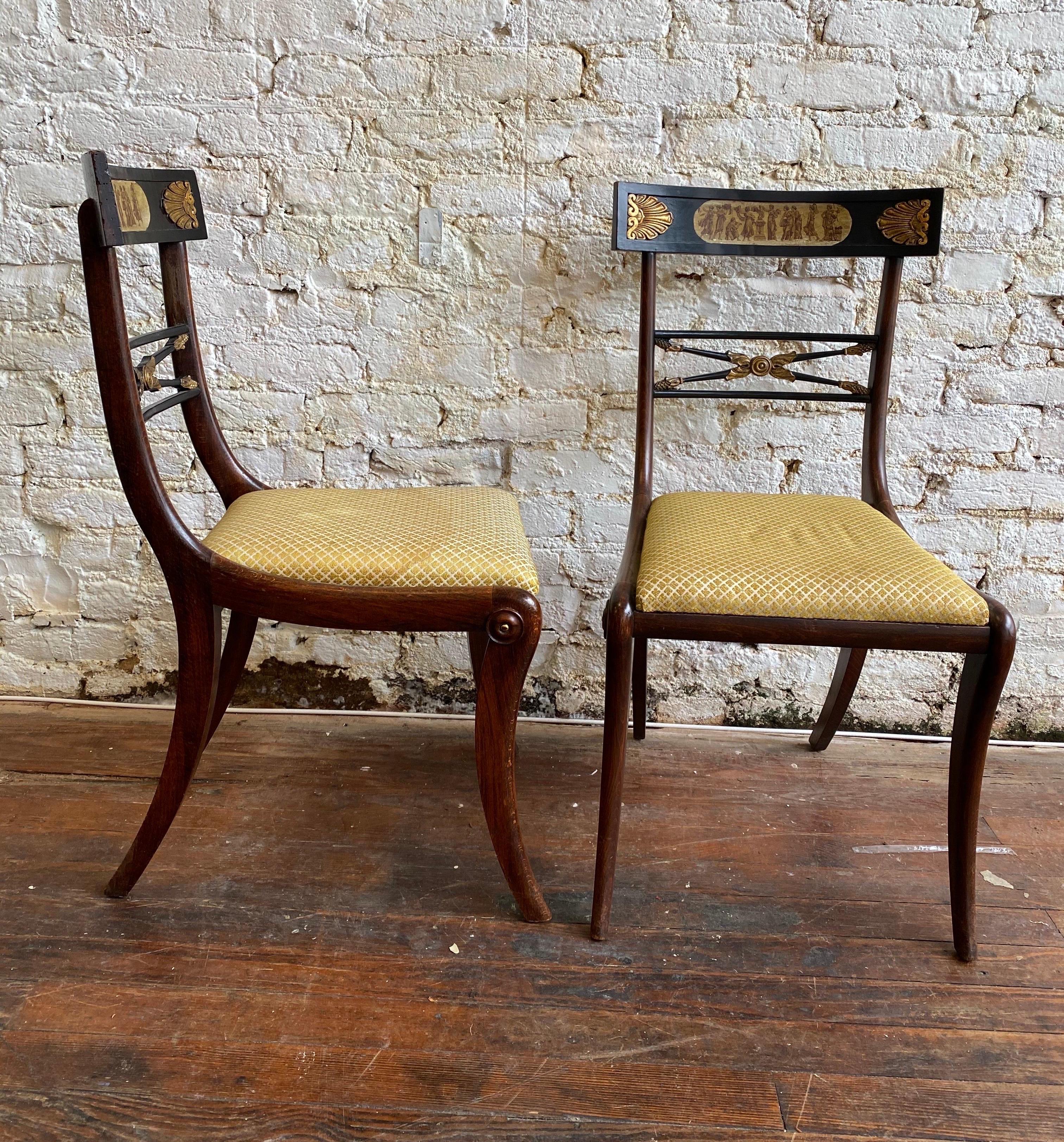 Great pair of 19th century English faux rosewood and ebonized side chairs with neoclassical scenes painted on the back rails and framed by raised and gilded carved ornamentation.
