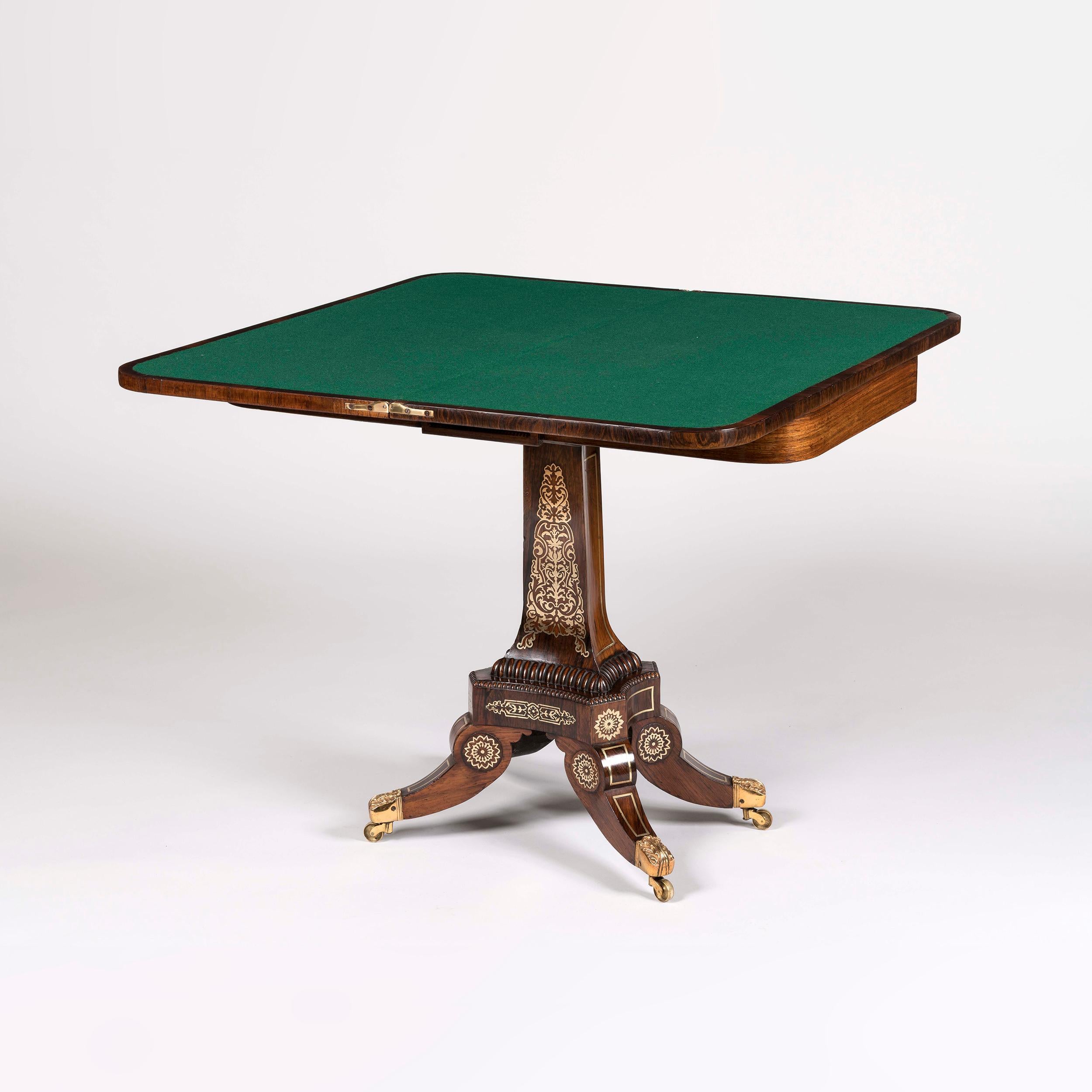 A pair of Regency card tables
 
Constructed in Gonçalo Alves, and dressed with extensive brass marquetry work; rising from quadripartite swept legs terminating in brass anthemion decorated toes with inset brass castors, conjoining incurved