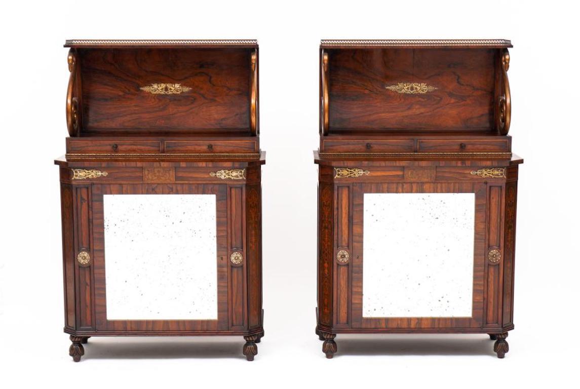 Pair of English Regency Style rosewood side cabinets

Pierced heart brass gallery over shelf, figural swan supports, figural winged angel ormolu decoration, two drawers. Canted corner base with foliate inlays, mirrored door over carved feet. Overall