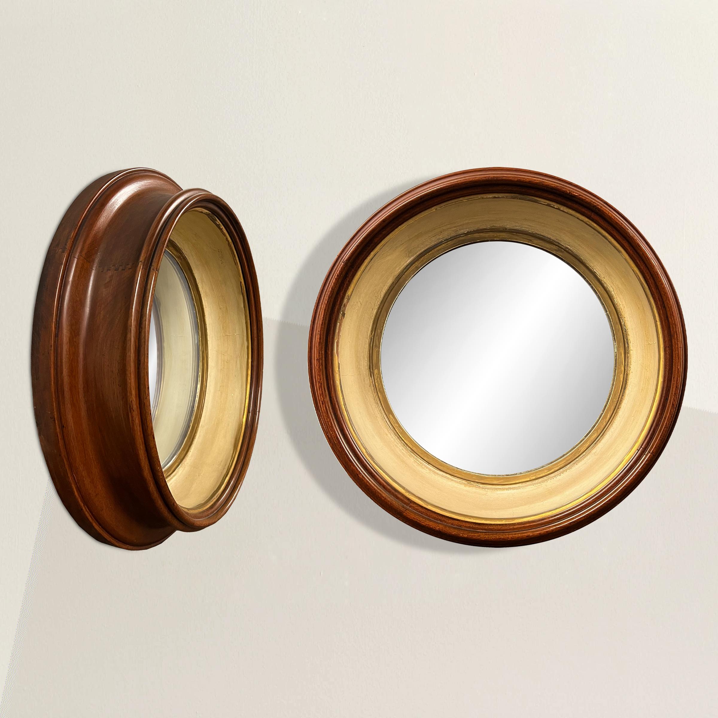Transform your living space with a pair of Georgian round mirrors that encapsulate the refinement of 19th-century English design. Crafted with an exceptional eye for detail, these mirrors boast unusually deep mahogany frames adorned with gold leaf