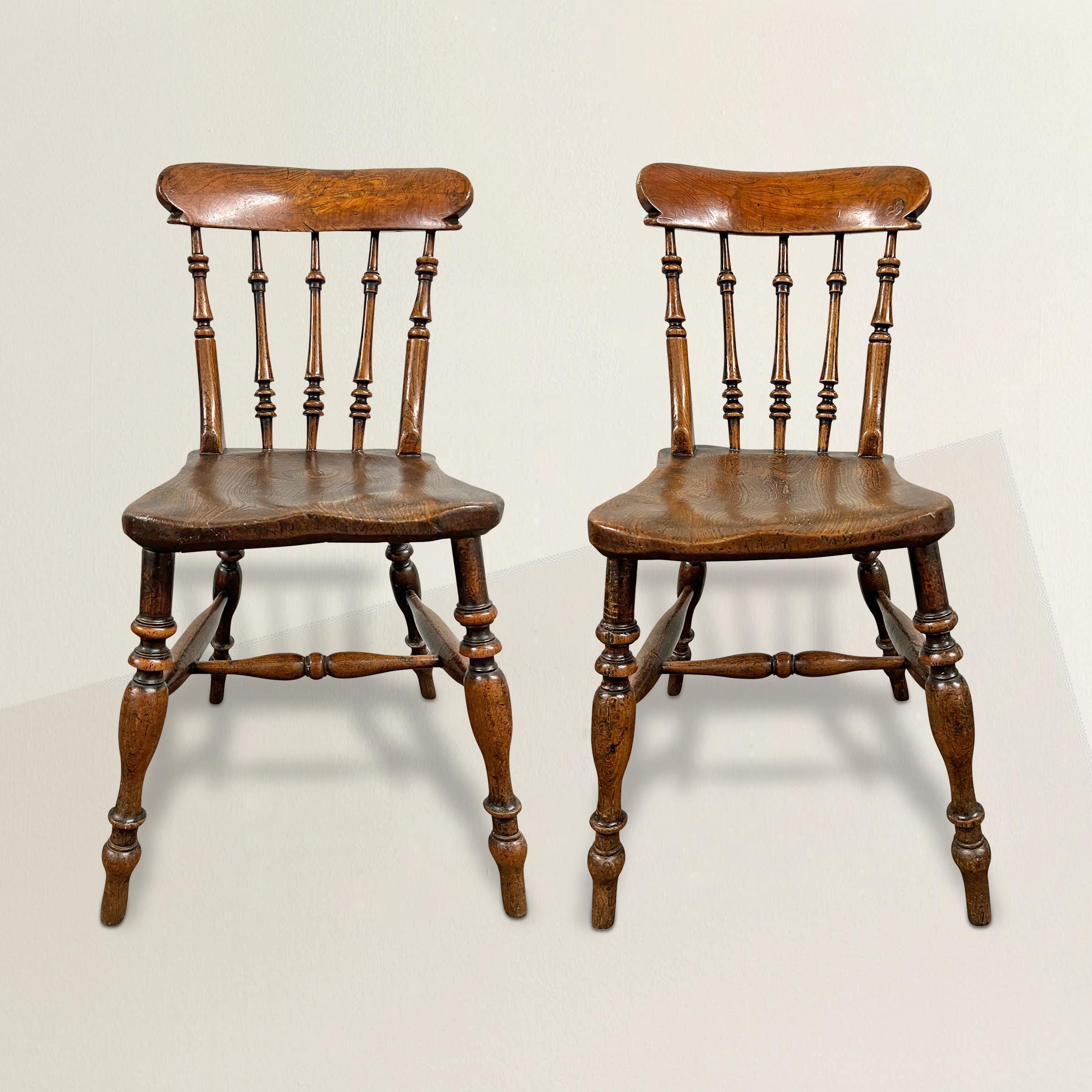 A stunning pair of early 19th century English elmwood side chairs, each with solid elm seats supported by turned legs and stretchers, and backs with turned splats supporting chunky crest rails, and one of the best patinas we've seen in a long time. 