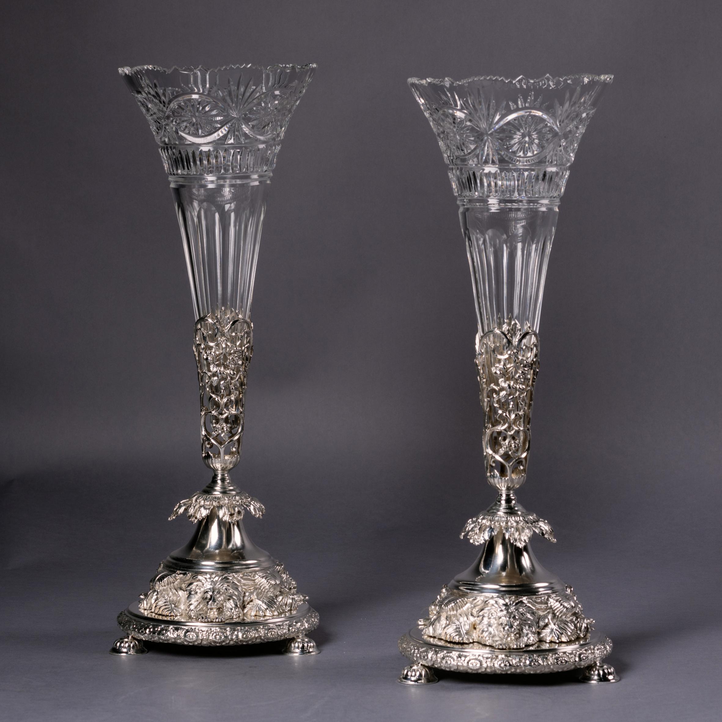 A pair of Victorian silver-plated and cut-glass vases by Joseph Rodgers & Sons. 

With marks for Joseph Rodgers & Son. Sheffield. 

Each vase having a cut-glass trumpet stem, the circular bases on openwork acanthus feet and lion-head supports