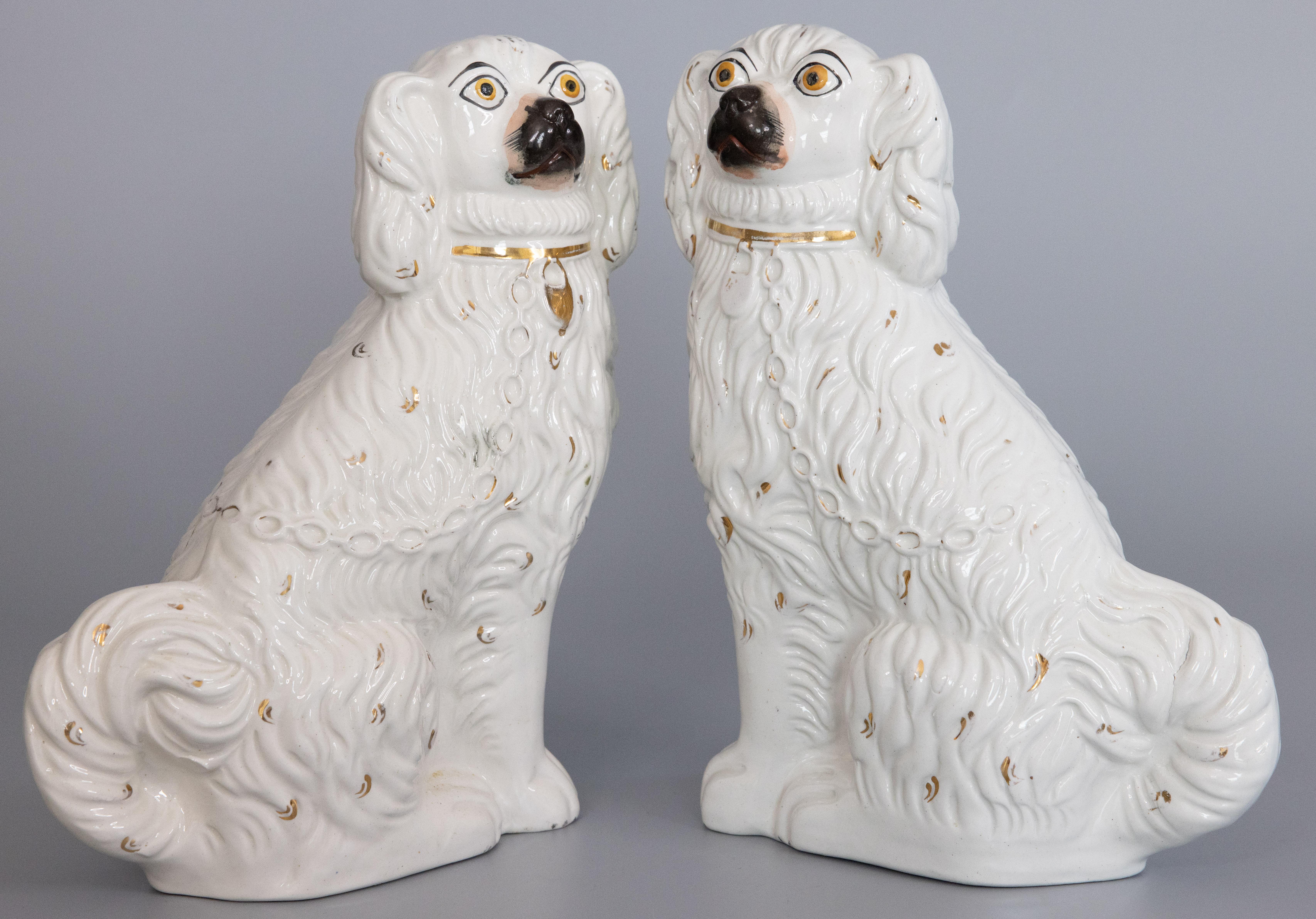 A fine pair of 19th Century English Staffordshire mantel dogs. These charming dogs are hand painted with lovely gilt details, sweet faces, and are a nice large size. They are the perfect Victorian pair of dogs for your mantel, bookcase or table.

